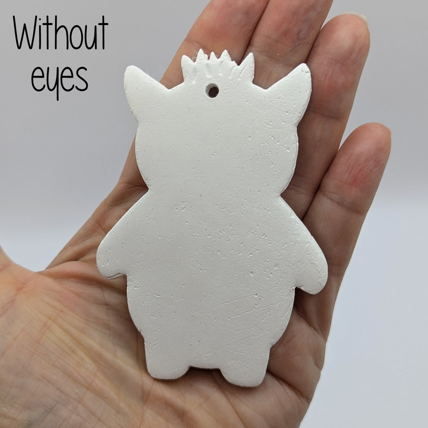 White silhouette of a funky monster with spikey hair, a pointy pair of ears, held in the palm of a hand