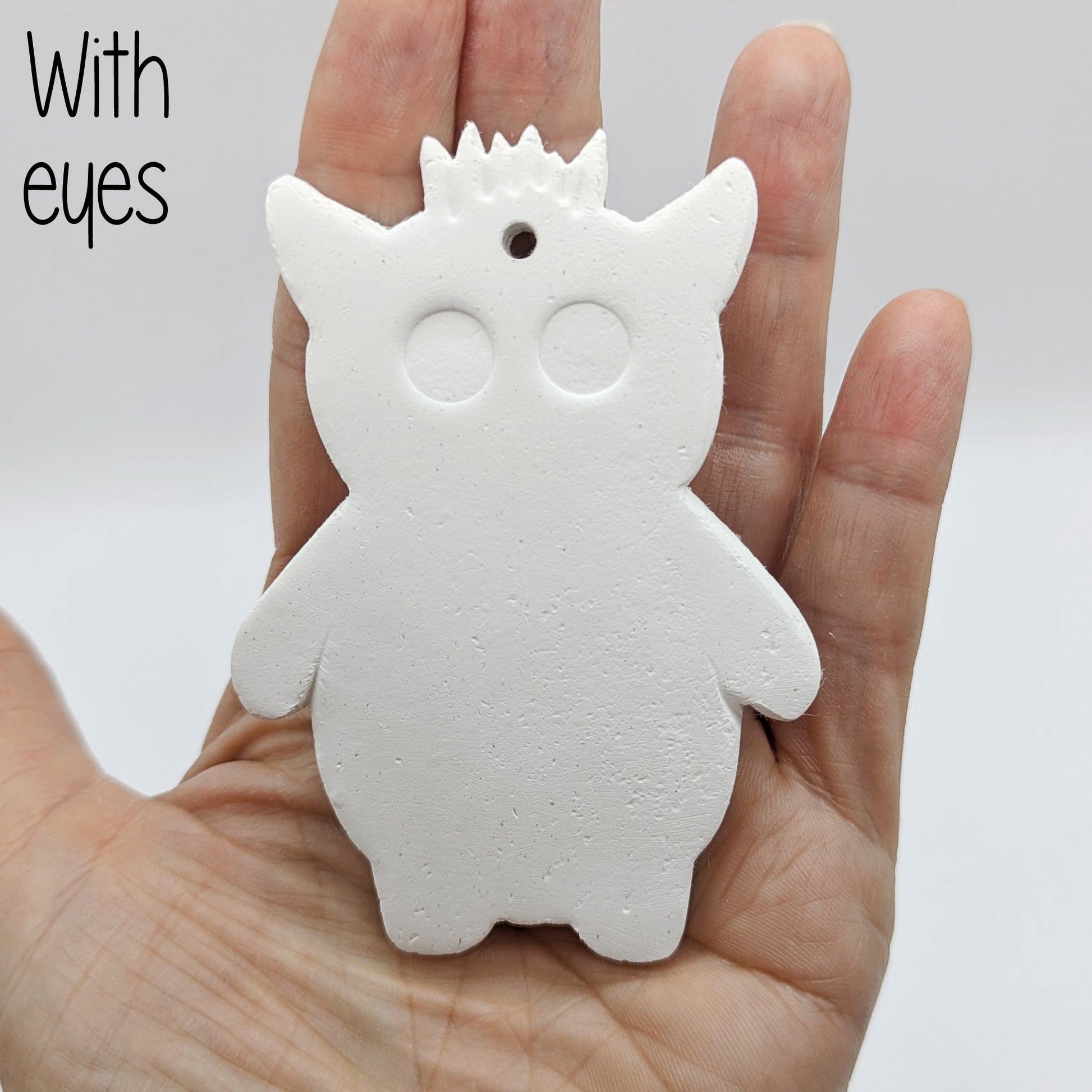 White silhouette of a funky monster with spikey hair, a pointy pair of ears, 21 large round eyes, held in the palm of a hand