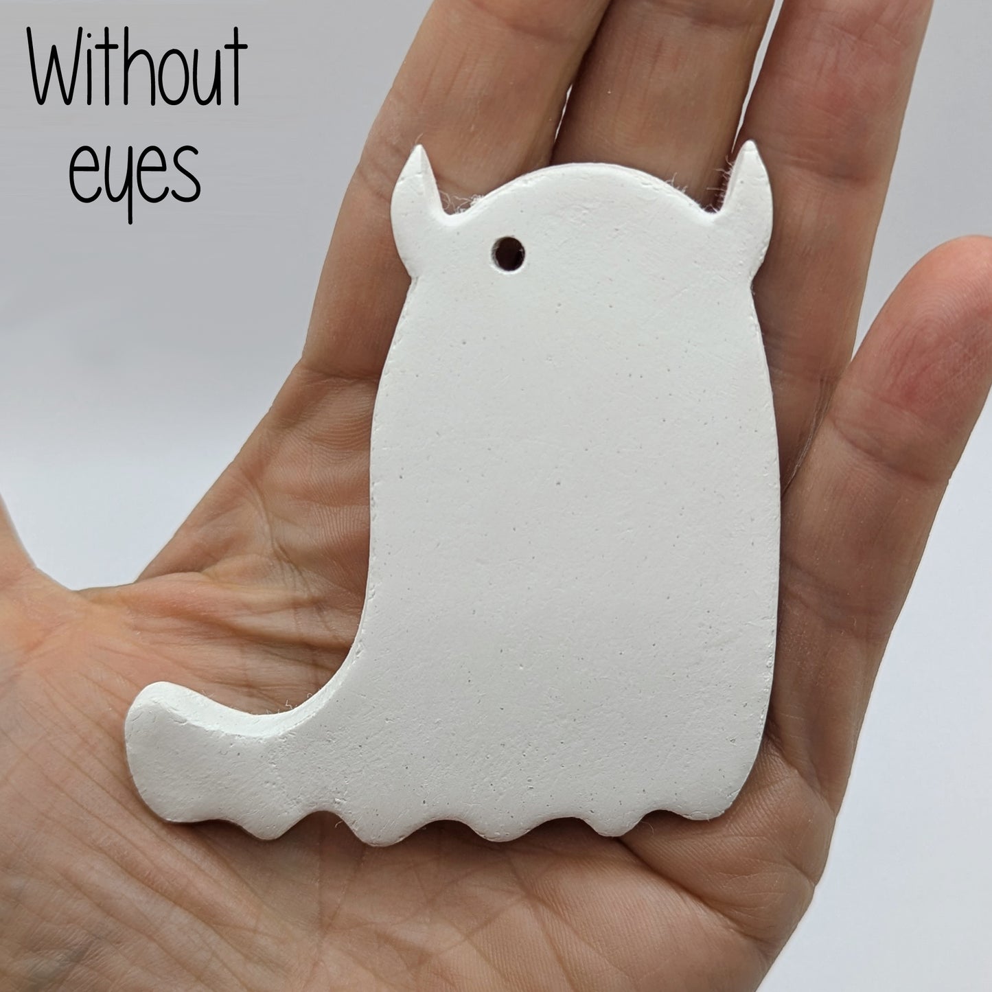 White ghost shaped air dried clay decoration - plain version, held in a hand