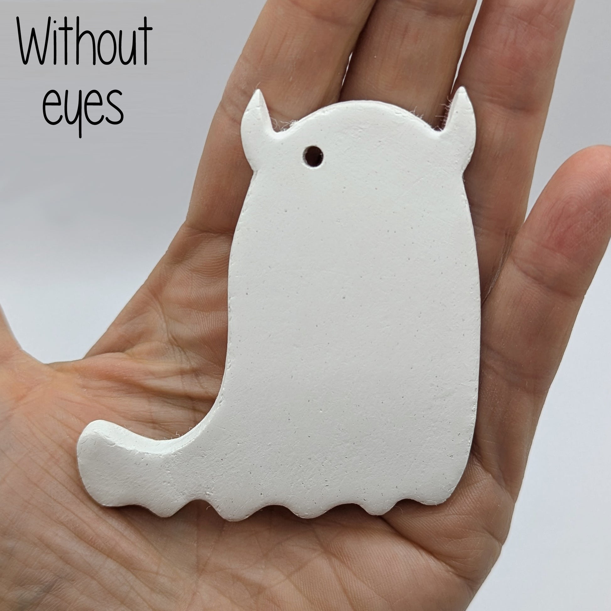 White ghost shaped air dried clay decoration - plain version, held in a hand