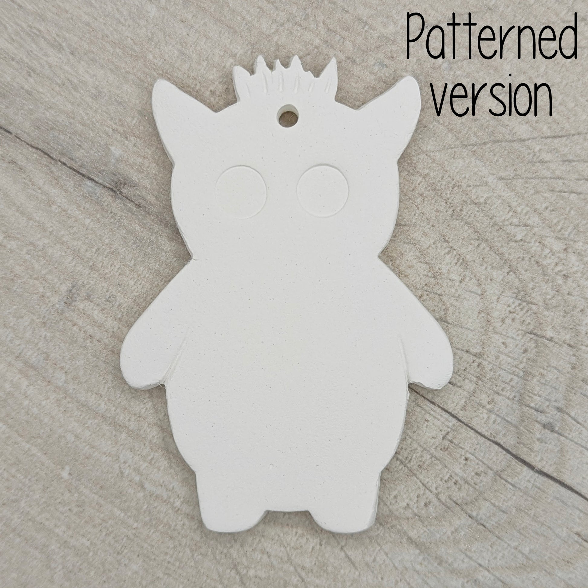 funky monster with spikey hair, a pointy pair of ears, 2 large round eyes, on a wooden surface