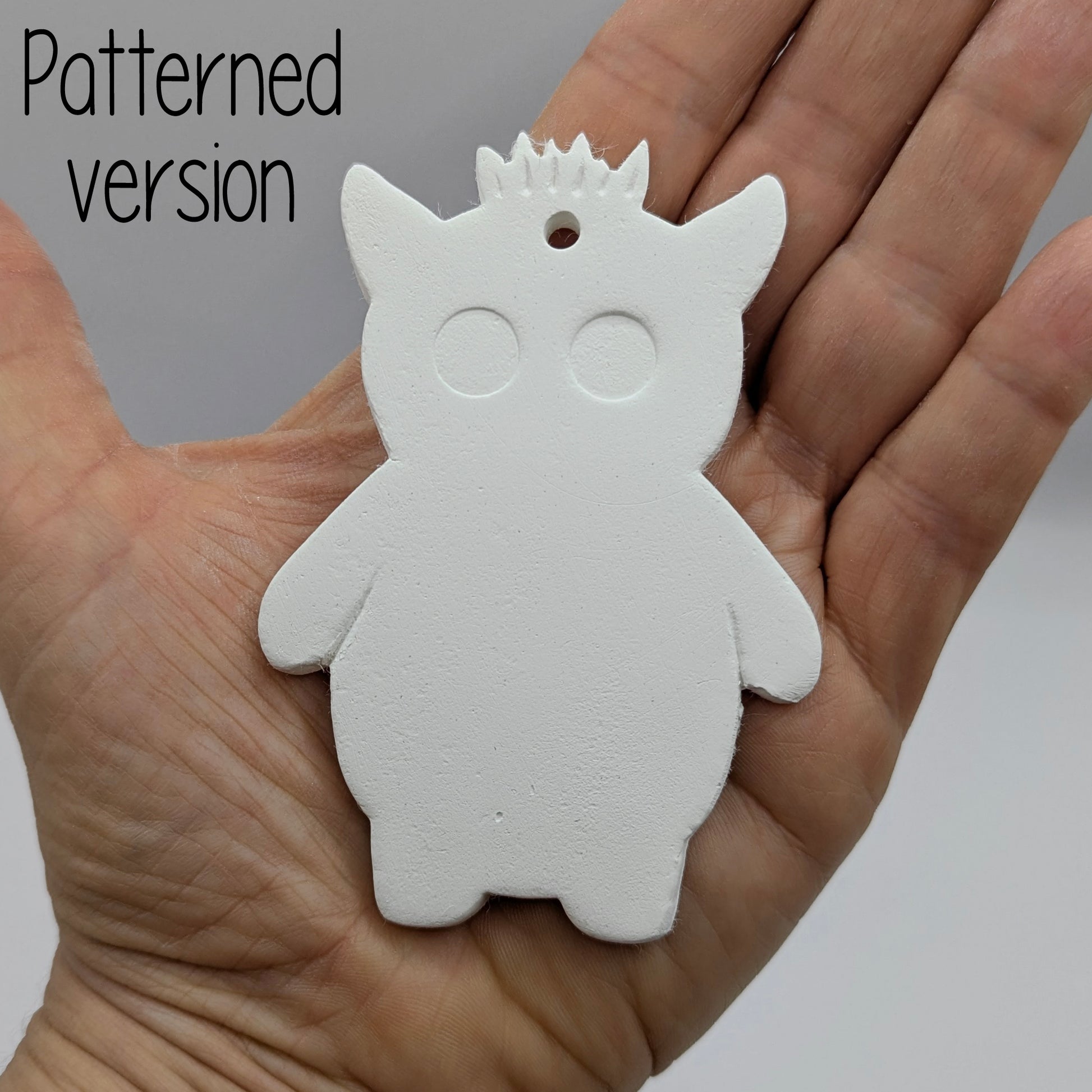 funky monster with spikey hair, a pointy pair of ears, 2 large round eyes, held in hand for scale