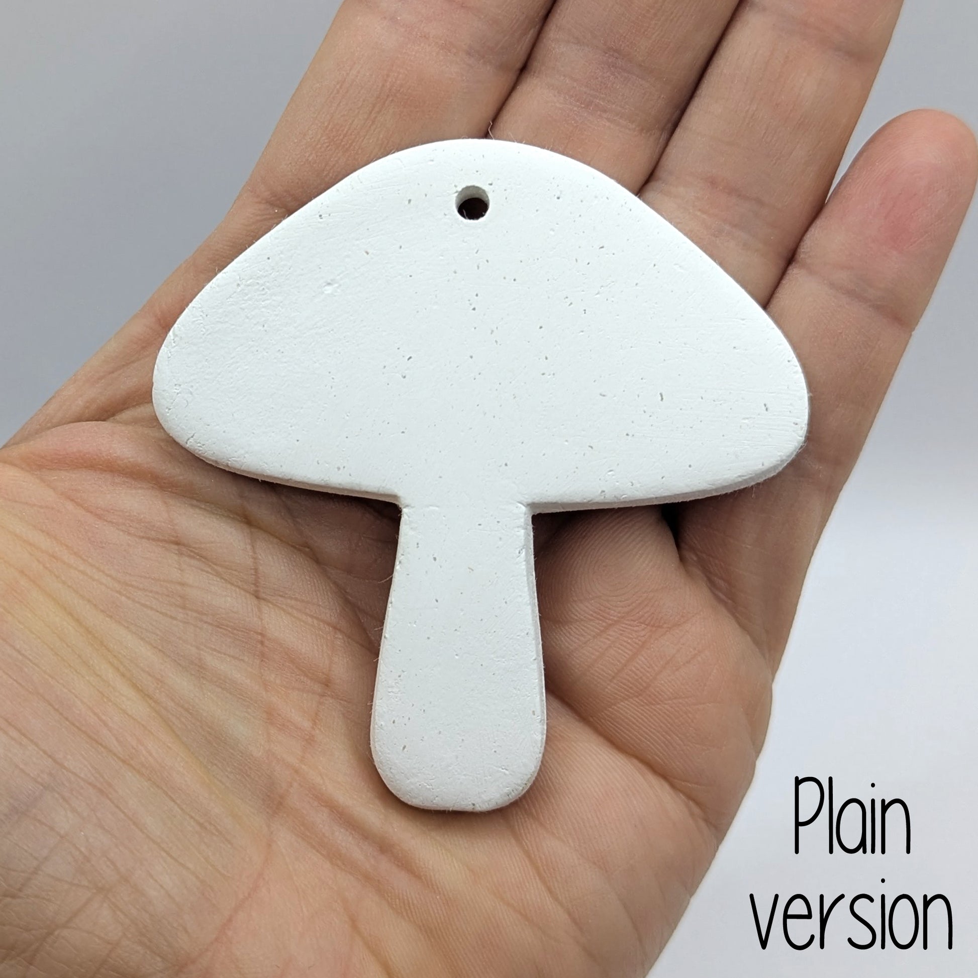 mushroom shaped clay decoration / tag, held in hand for scale, plain version