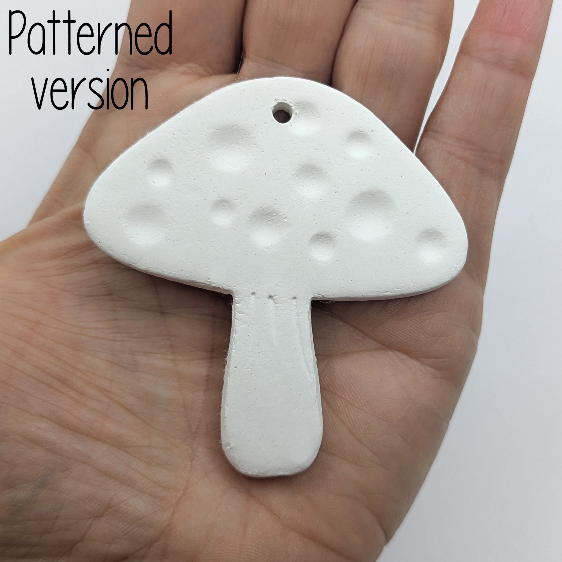 mushroom shaped clay decoration / tag, held in hand for scale, patterned version
