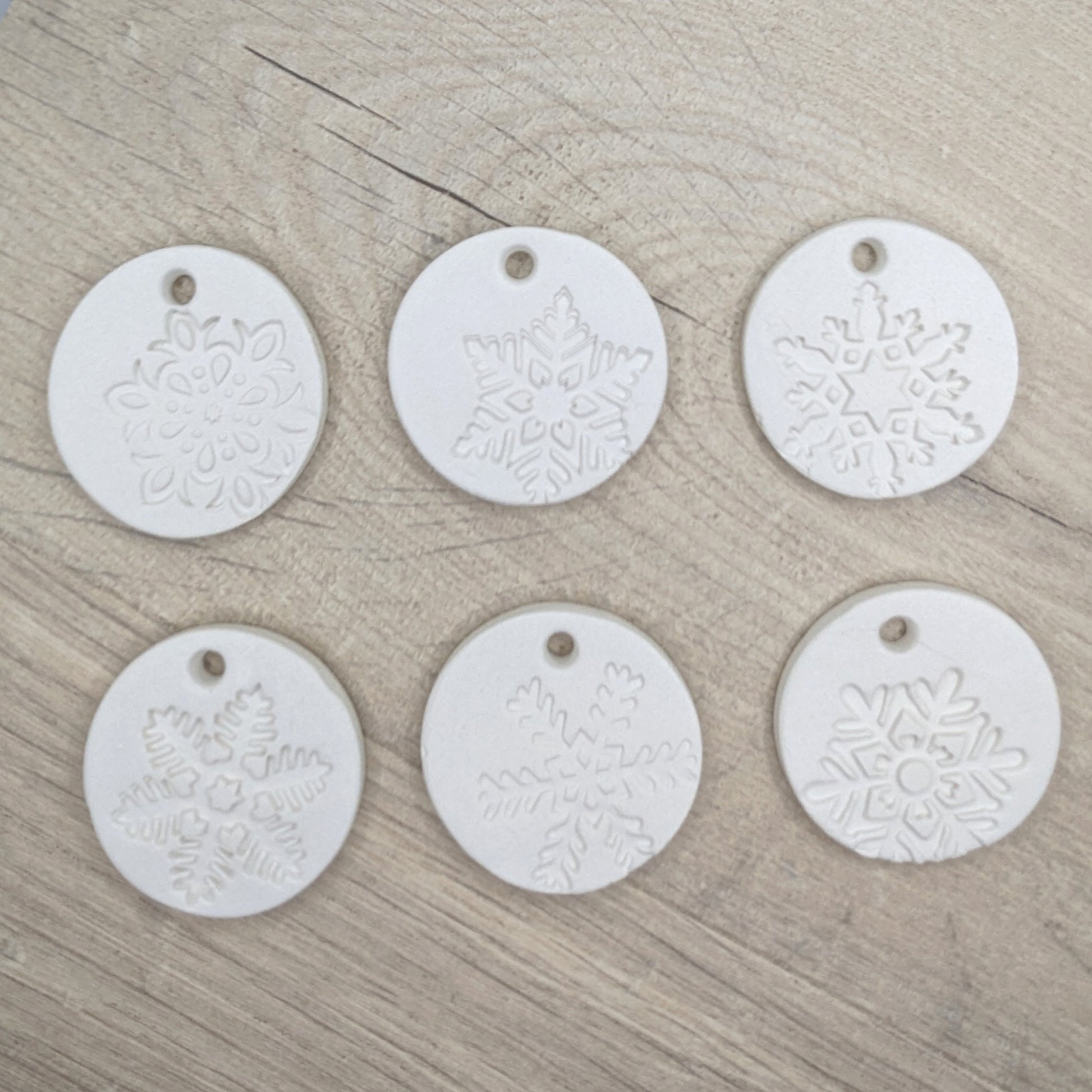 set of six white clay tags with snowflake patterns on - to show different designs