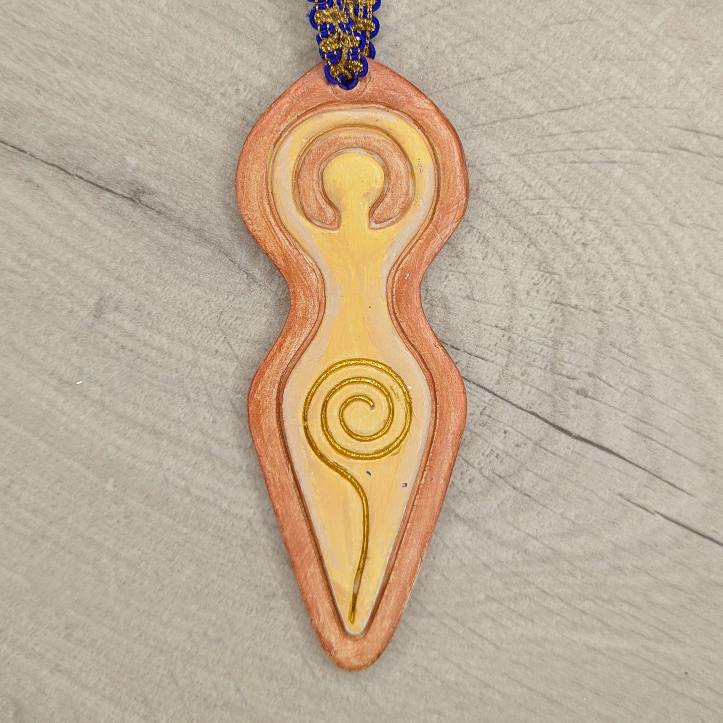 spiral goddess decoration painted in brown and yellow shades on a wooden background