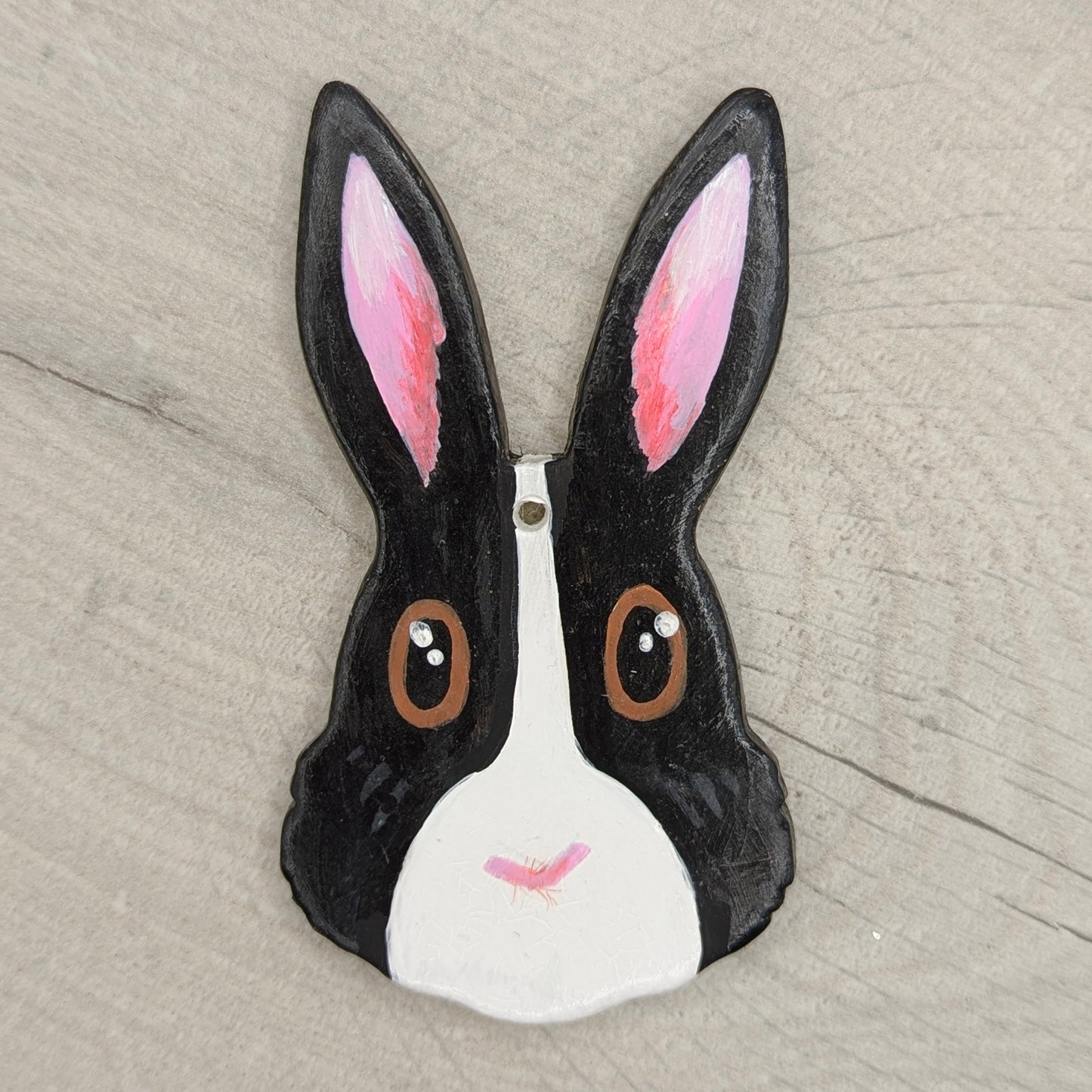 painted decorative rabbit face with black ears and white face on a wooden surface