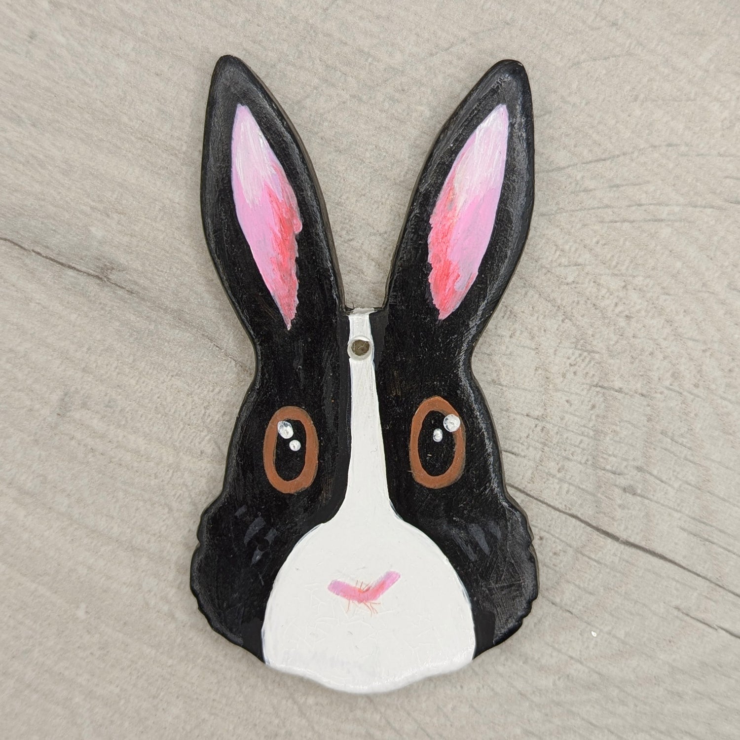painted decorative rabbit face with black ears and white face on a wooden surface