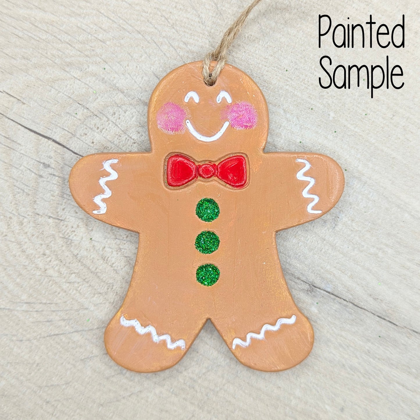 Painted gingerbread man ornament on a wooden surface with 'Painted Sample' text.