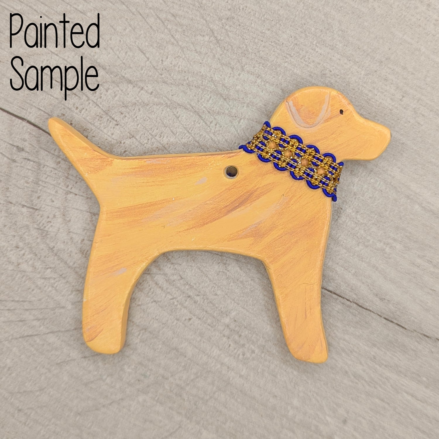 Dog-shaped clay shaped decoration with a blue and gold ribbon collar on a wooden surface