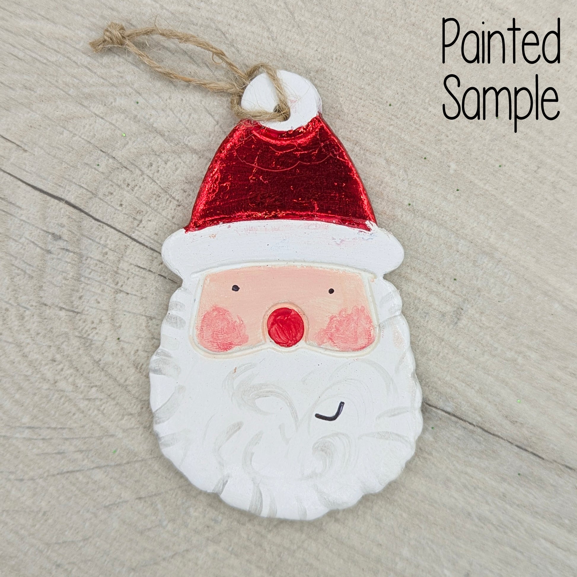 Painted Santa Claus face ornament on a wooden surface with 'Painted Sample' text displayed top right.