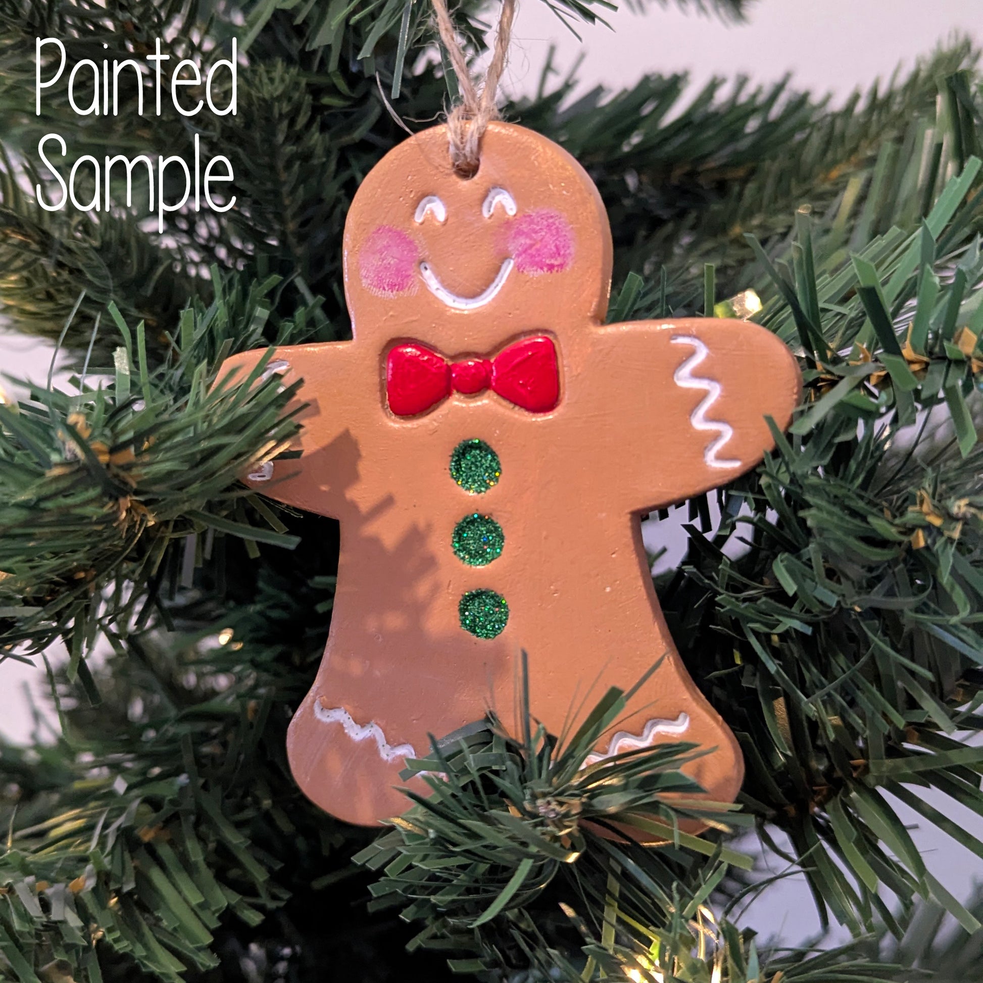 Painted gingerbread man ornament on a Christmas tree with 'Painted Sample' text.