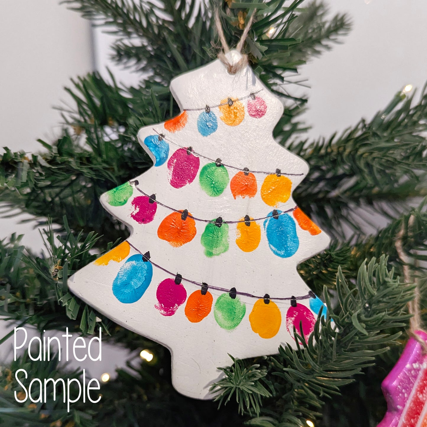 Christmas tree-shaped ornament with colorful fingerprint lights design painted on it, displayed on a christmas tree 