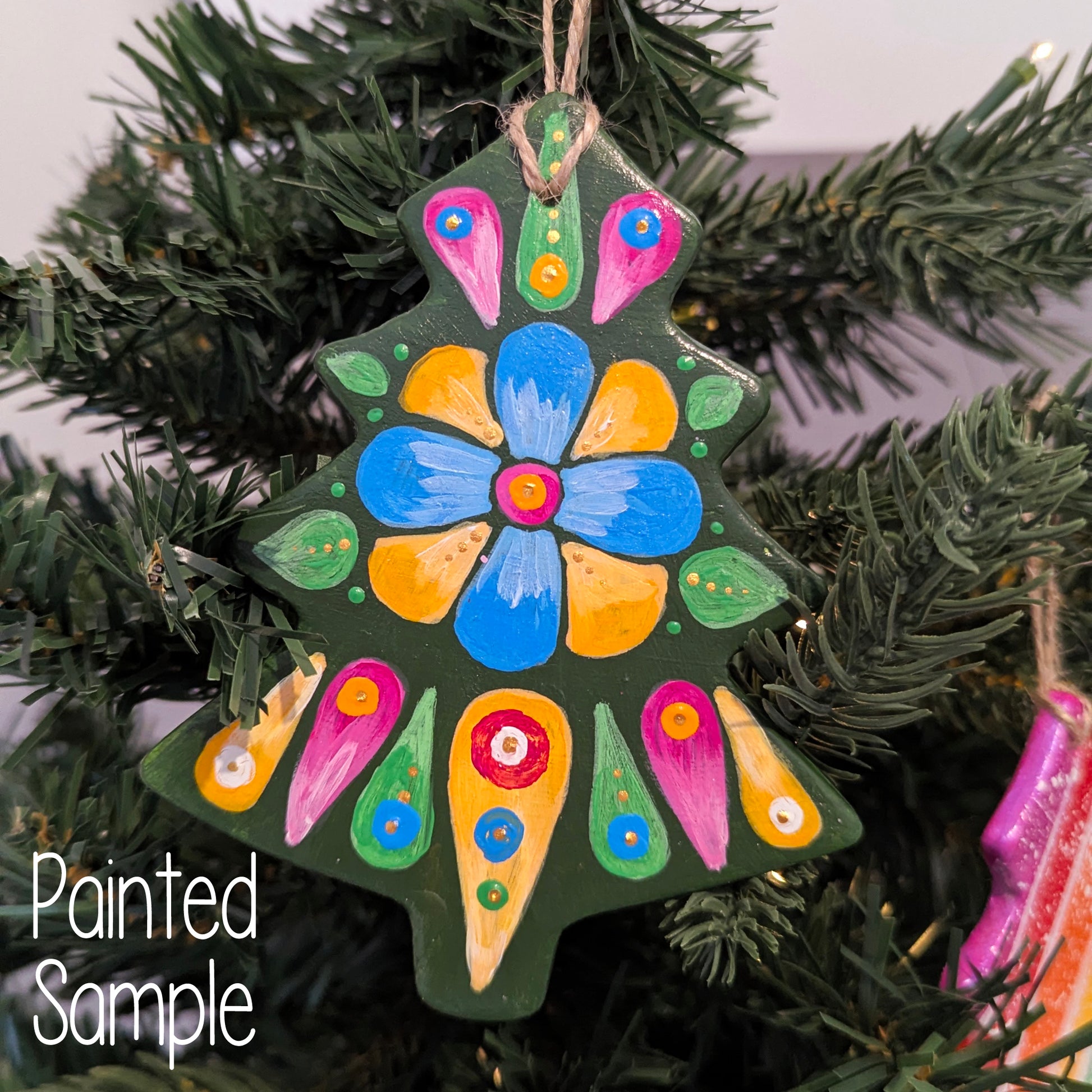 Colorful painted Christmas tree ornament on green christs tree