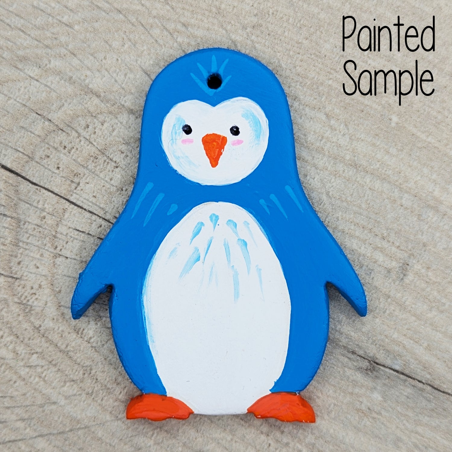 clay penguin sample decoration, painted in a funky bright blue, with white belly and orange feet and beak