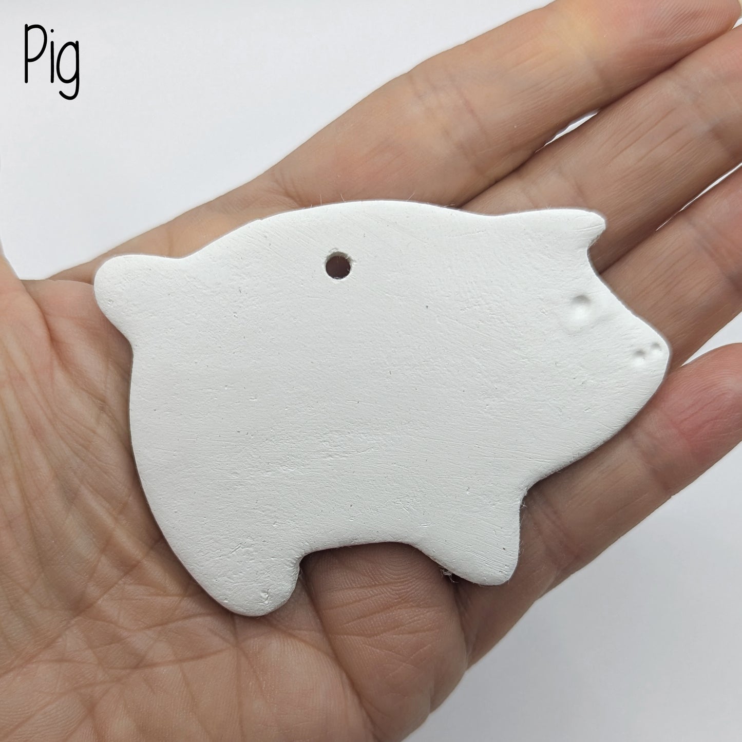air dried clay decoration in the shape of a pig, shown in hand for scale