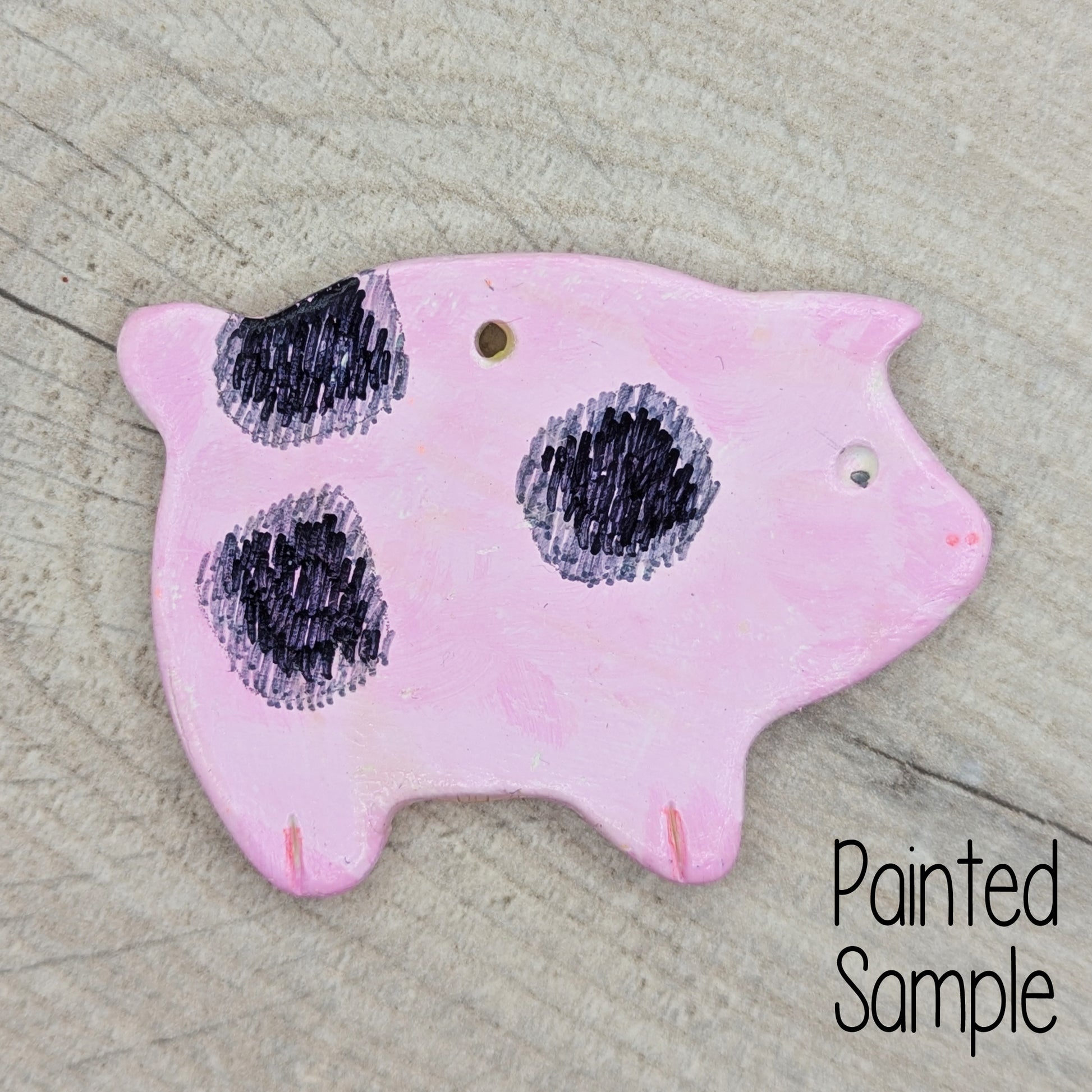 painted sample of clay pig decoration, painted in pale pink with black spots