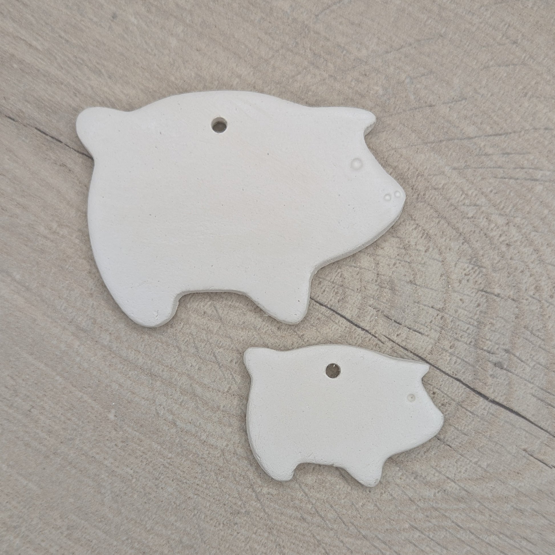 air dried clay decoration in the shape of a piglet and pig to shown them together and the scale