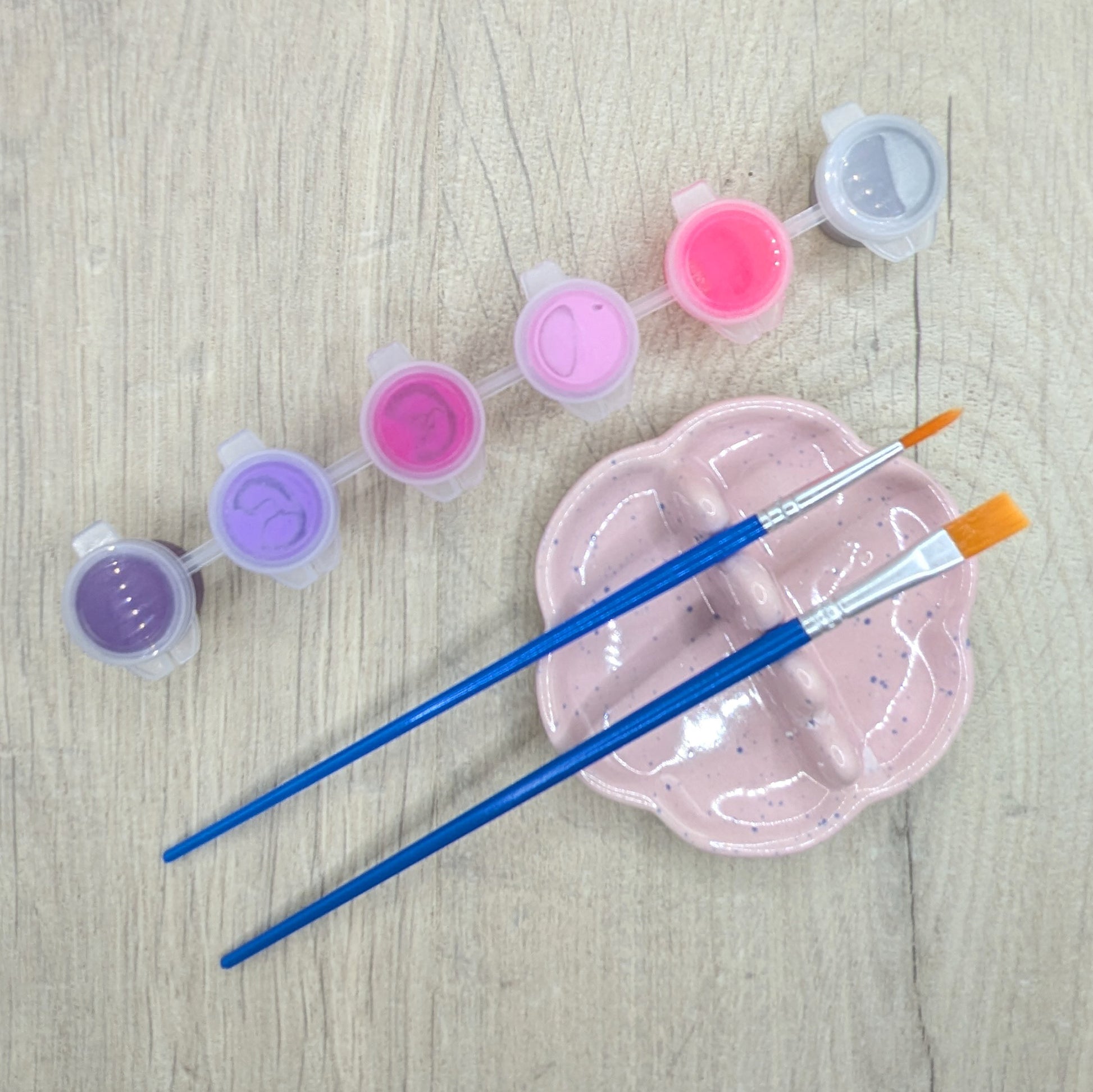 paint kit, showing 6 paints, purple, lilac, deep pink, light pink, bright pink and silver with 2 brushes