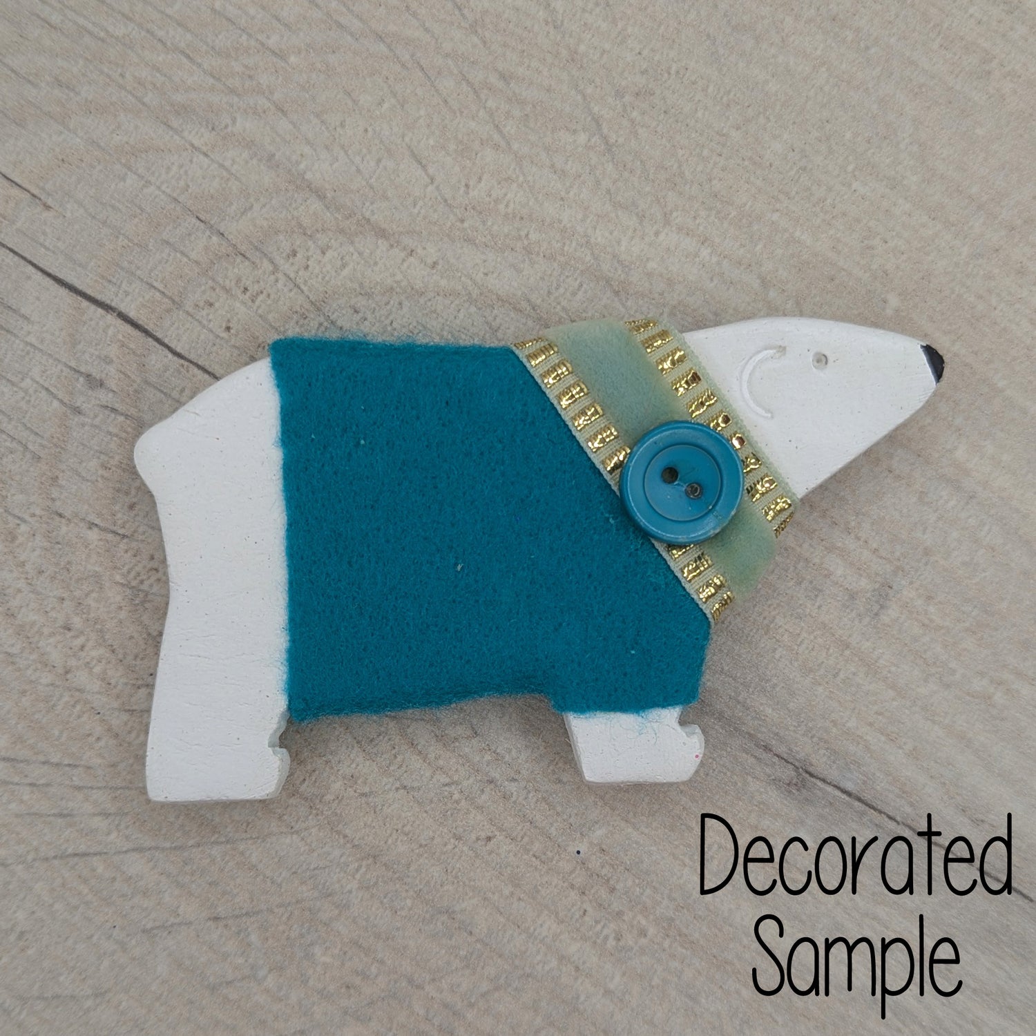 polar bear clay decoration, decorated by adding a teal felt jumper with Christmas ribbon and a button around the neck