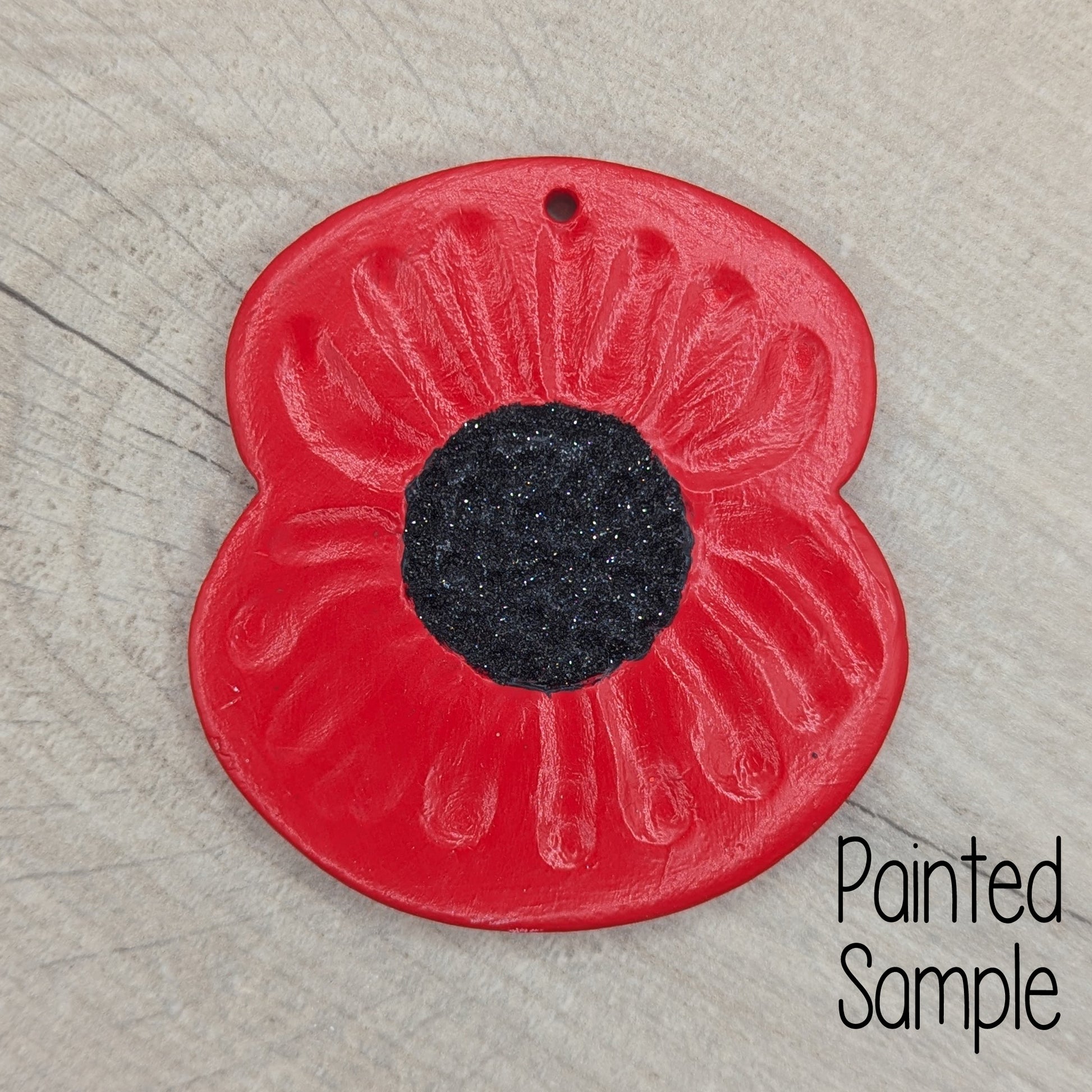 poppy decoration painted with red petals and a black glitter centre