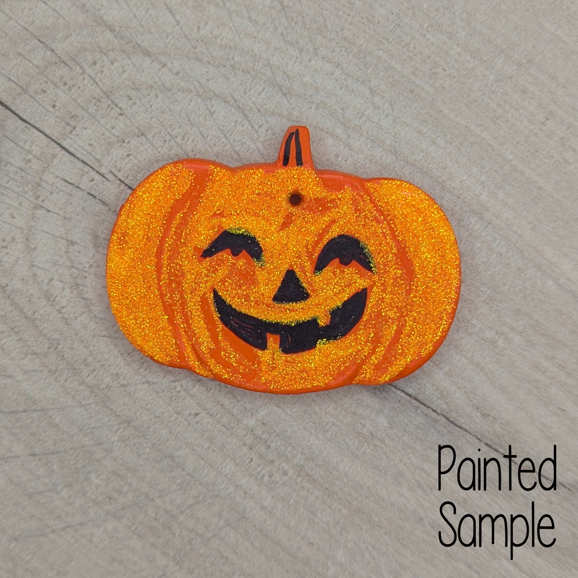 halloween pumpkin sample decoration, painted in orange with a cute spooky black face, with orange glitter all over