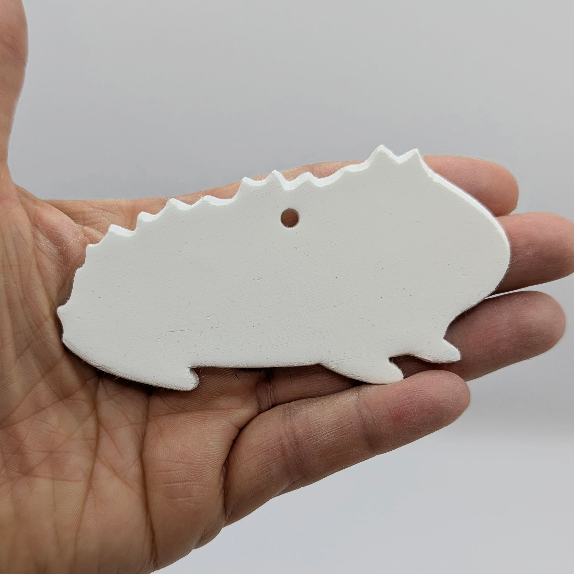 white guinea pig shaped decoration made out of air dried clay shown on a light wood background