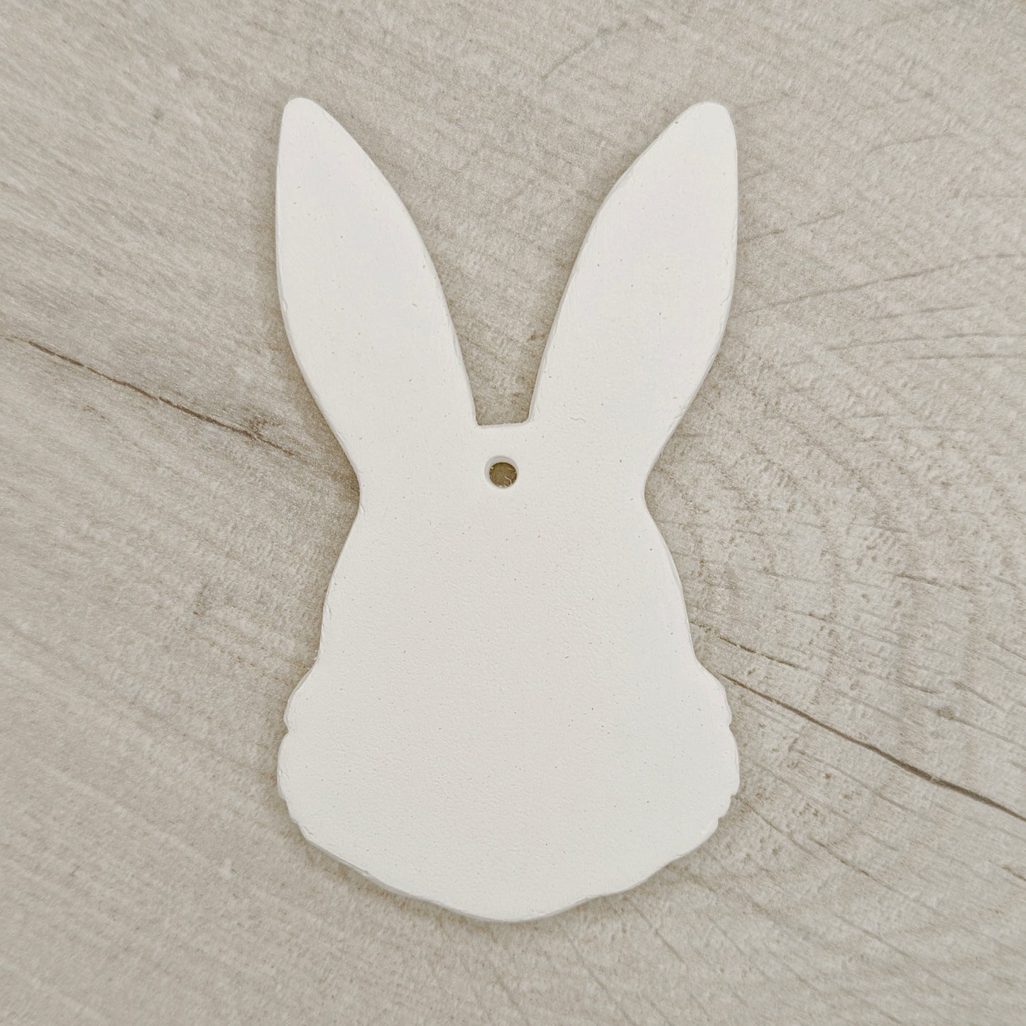 White clay bunny-shaped decoration on a wooden surface