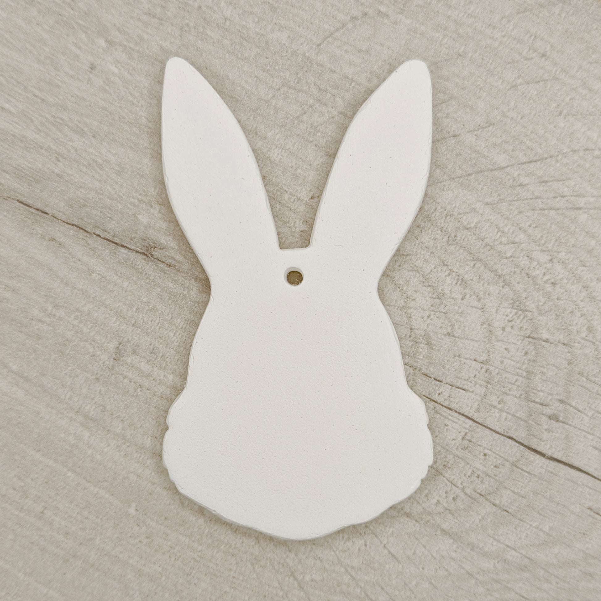 White clay bunny-shaped decoration on a wooden surface