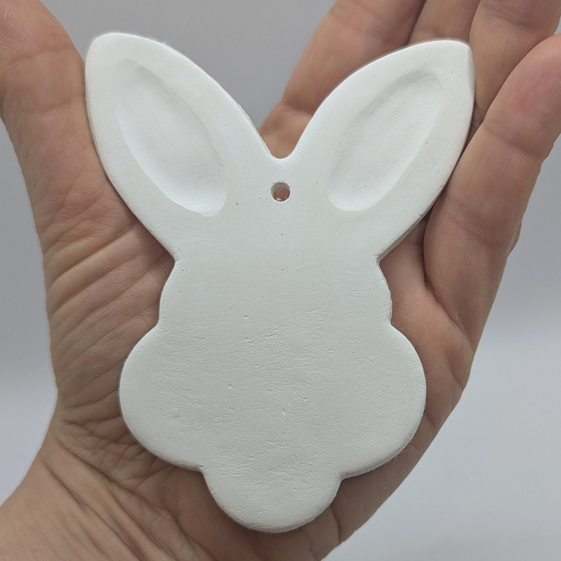 rabbit face clay decoration shown in some ones hand to show size