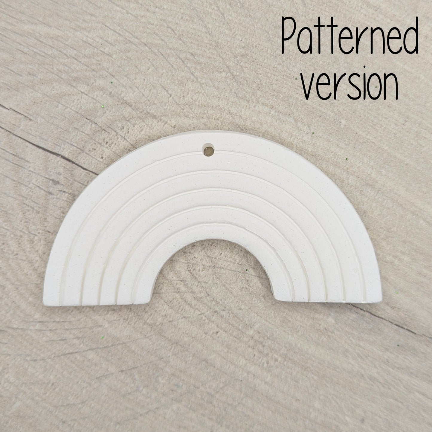 White rainbow-shaped arch ornament on a beige wooden surface 