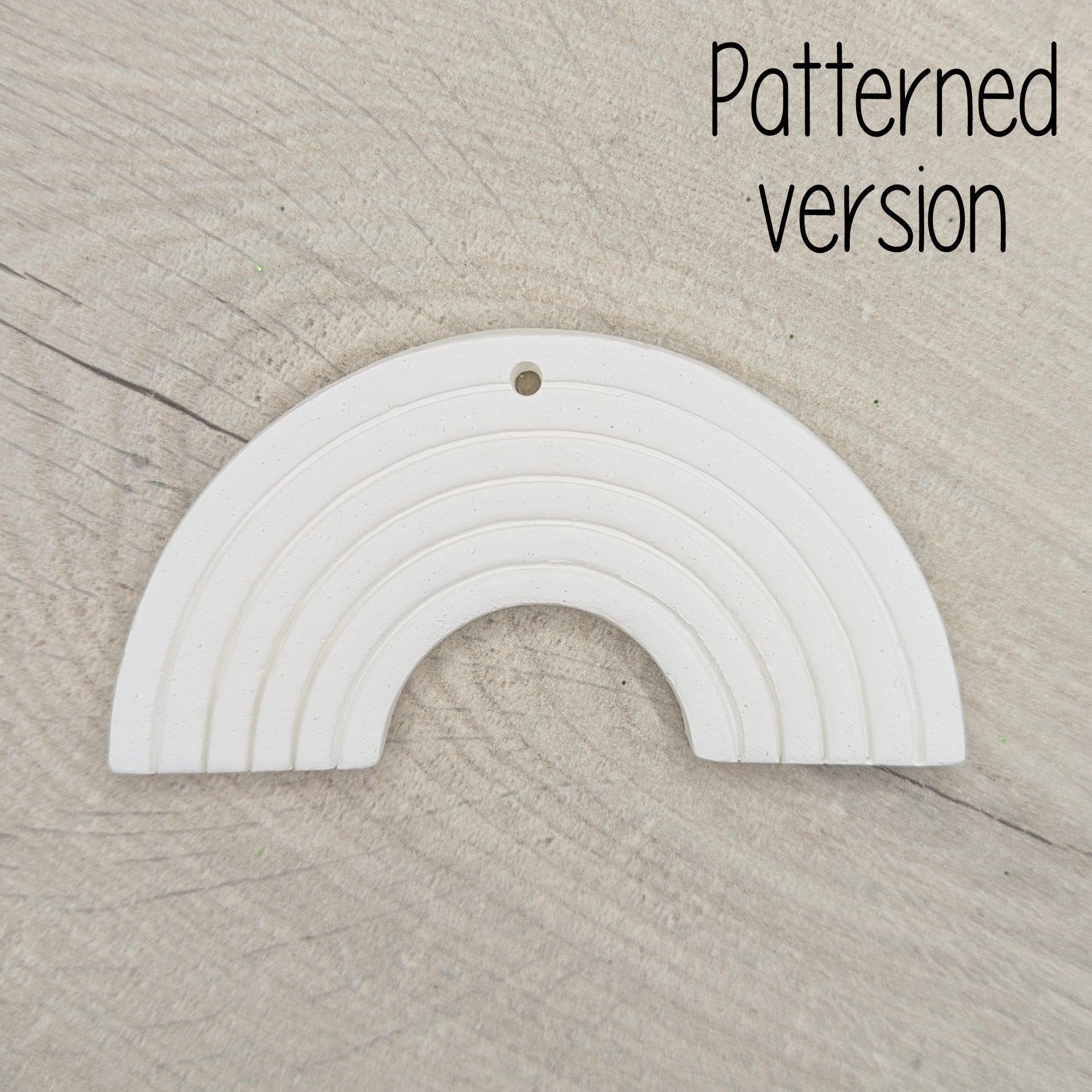 White rainbow-shaped arch ornament on a beige wooden surface 