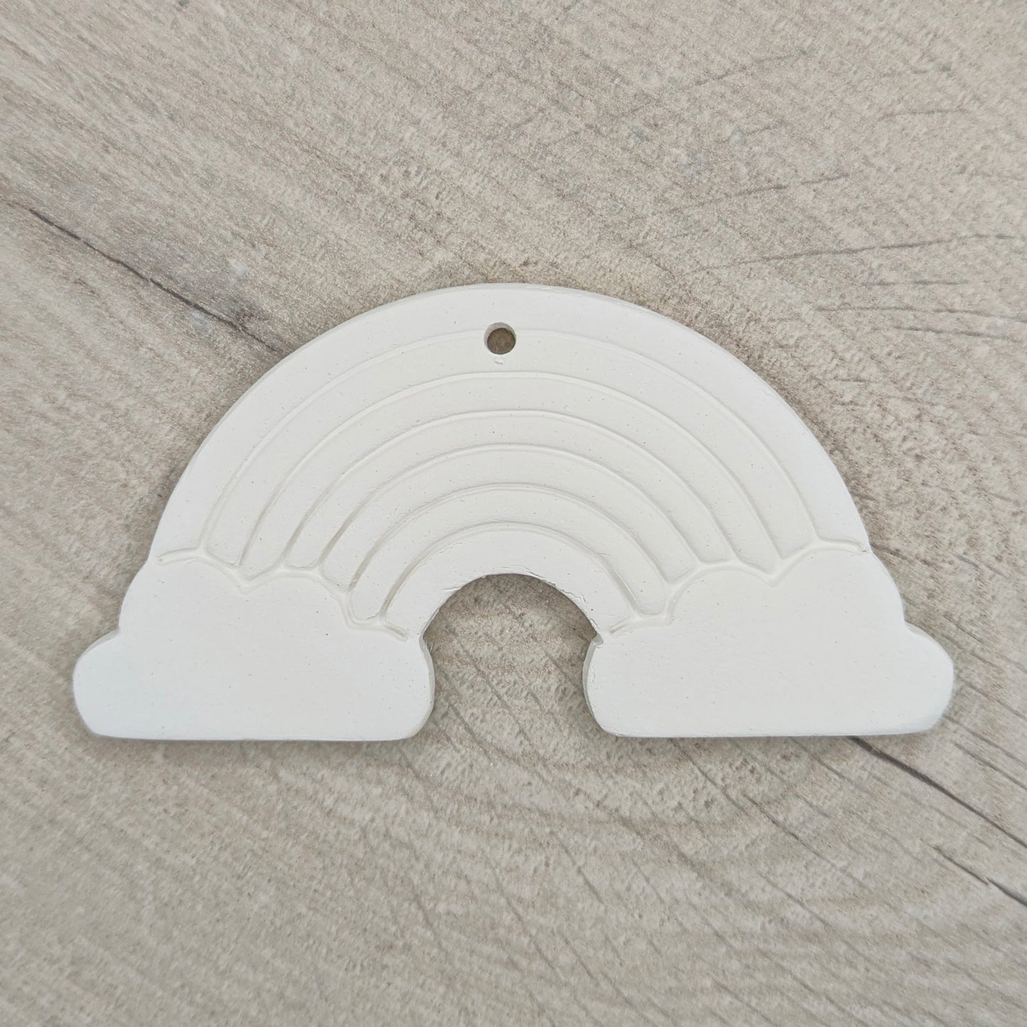white air dried clay rainbow decoration shown on a light wood background