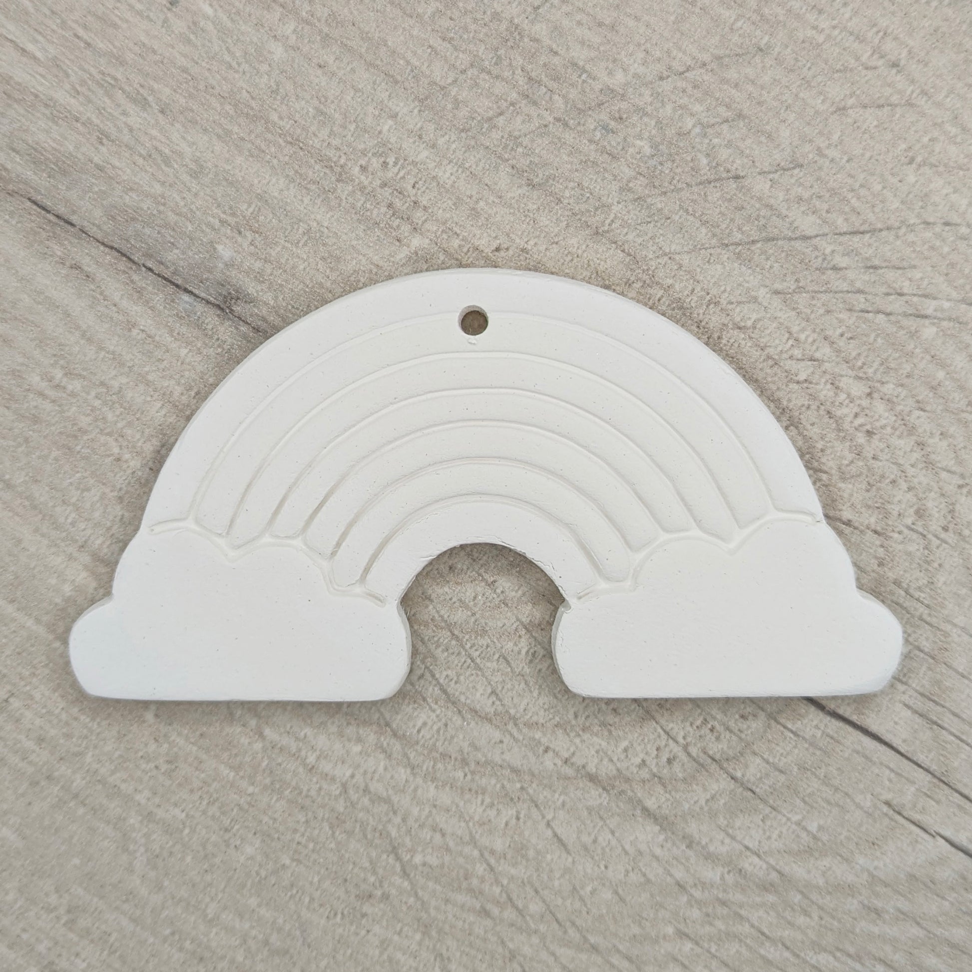 white air dried clay rainbow decoration shown on a light wood background