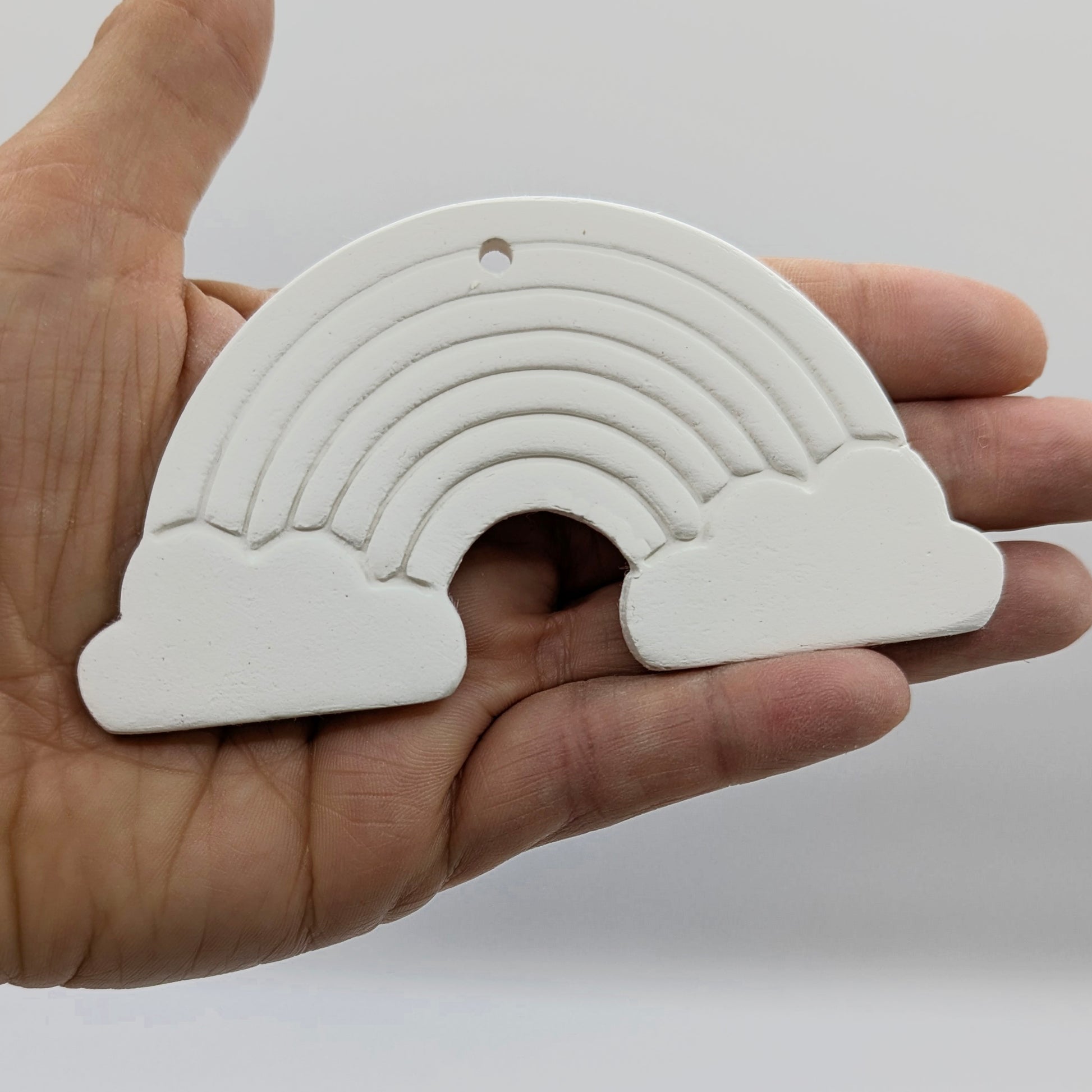 white air dried clay rainbow decoration shown in some ones hand for scale