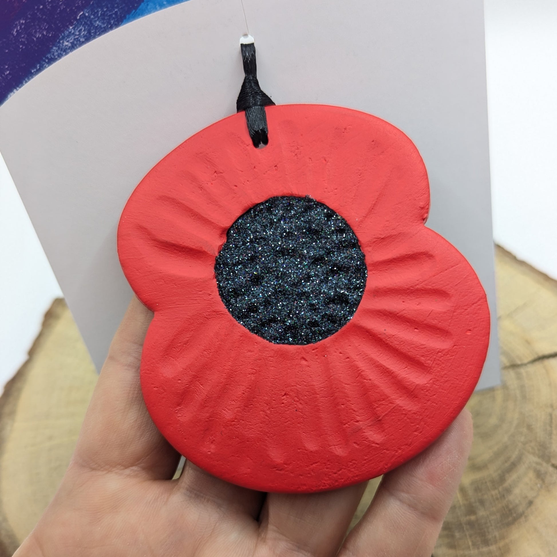 close up of clay poppy decoration been held in a hand to show size