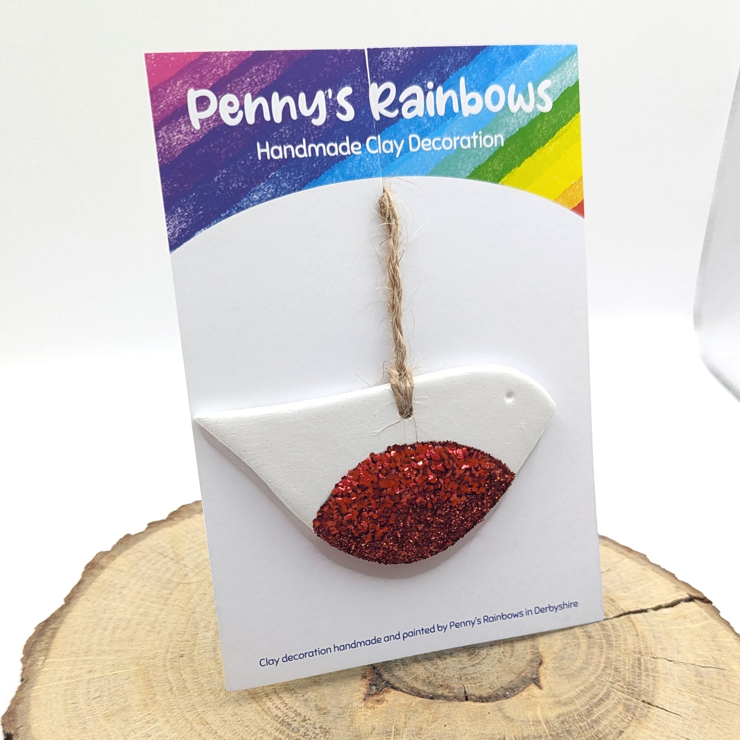 Handmade robin clay decoration with red glitter on chest of robin on a 'Penny's Rainbows' branded card