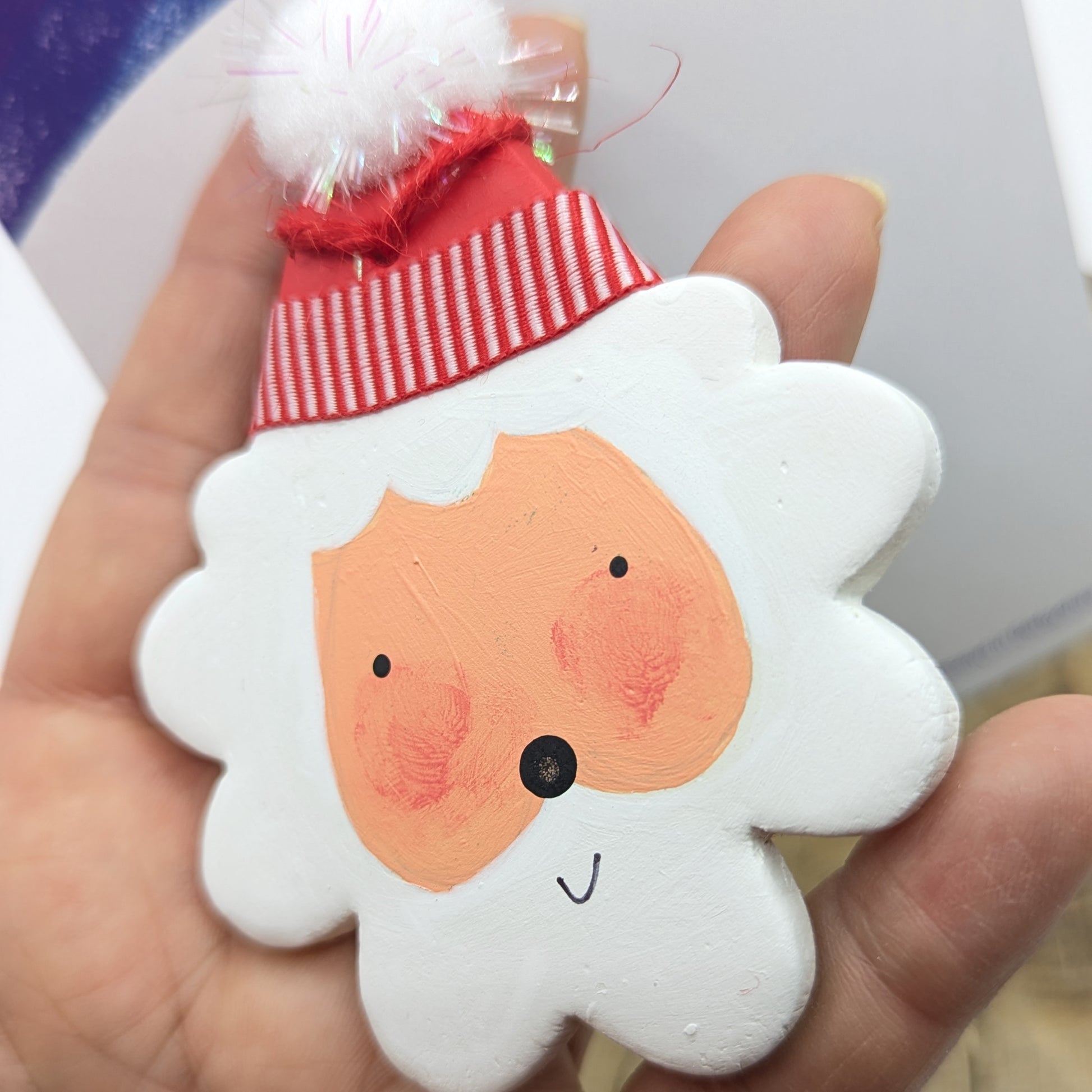 hand holding a santa decoration, all painted ready to hang on xmas tree