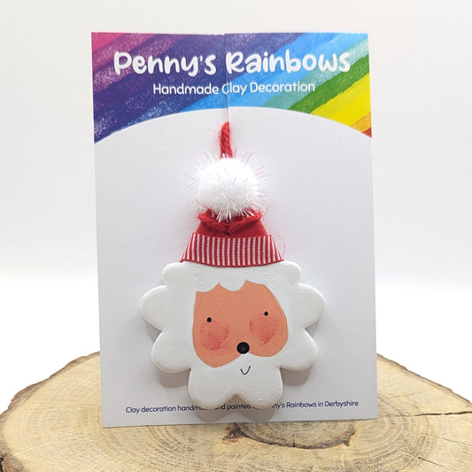 Penny's Rainbows handmade clay painted santa decoration on a white card with colorful border