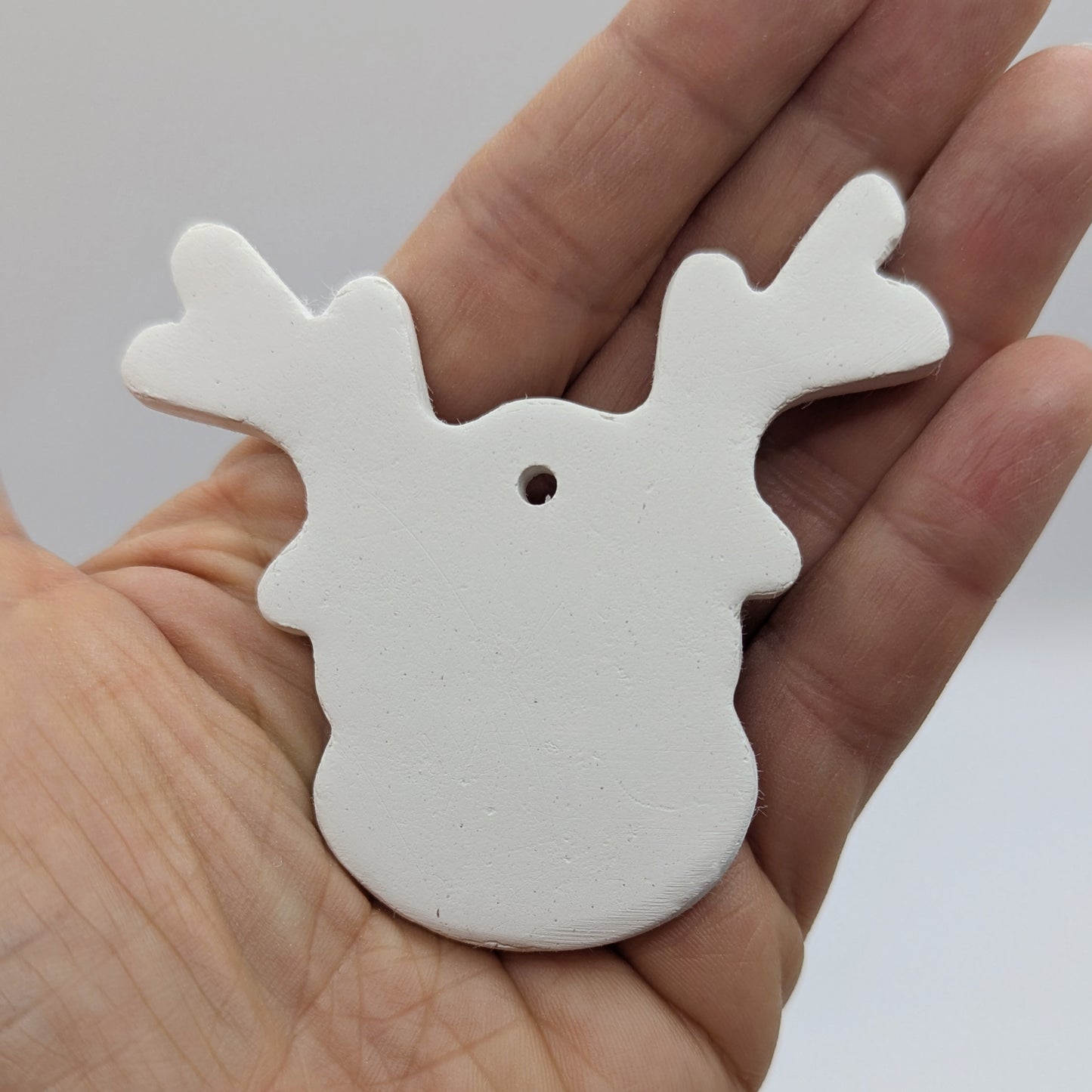 clay reindeer decoration held in palm of hand to show size