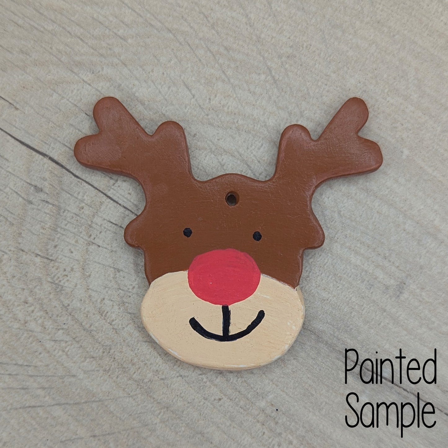 painted reindeer clay decoration, painted in brown and beige with a large red nose and smiley mouth 