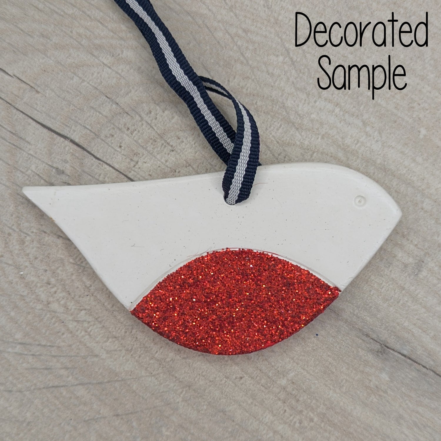 Christmas style robin clay decoration, with a red glitter chest, black and white ribbon to hang it