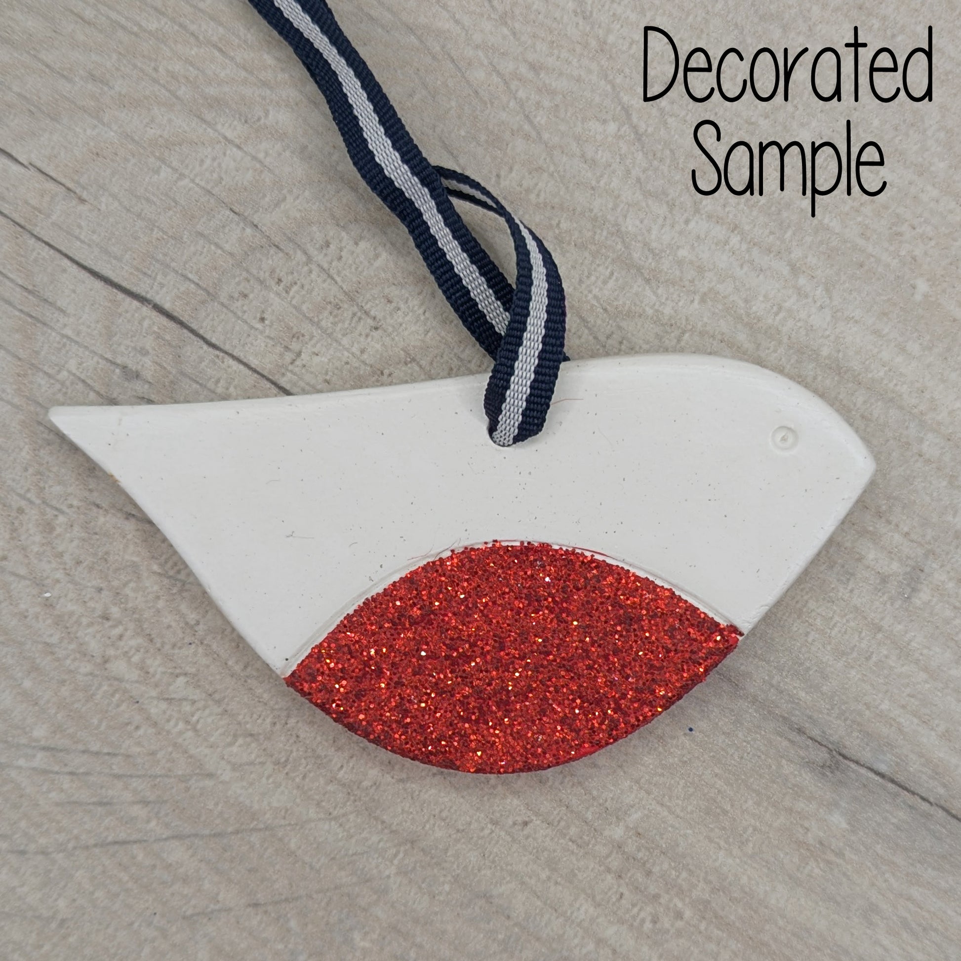 Christmas style robin clay decoration, with a red glitter chest, black and white ribbon to hang it