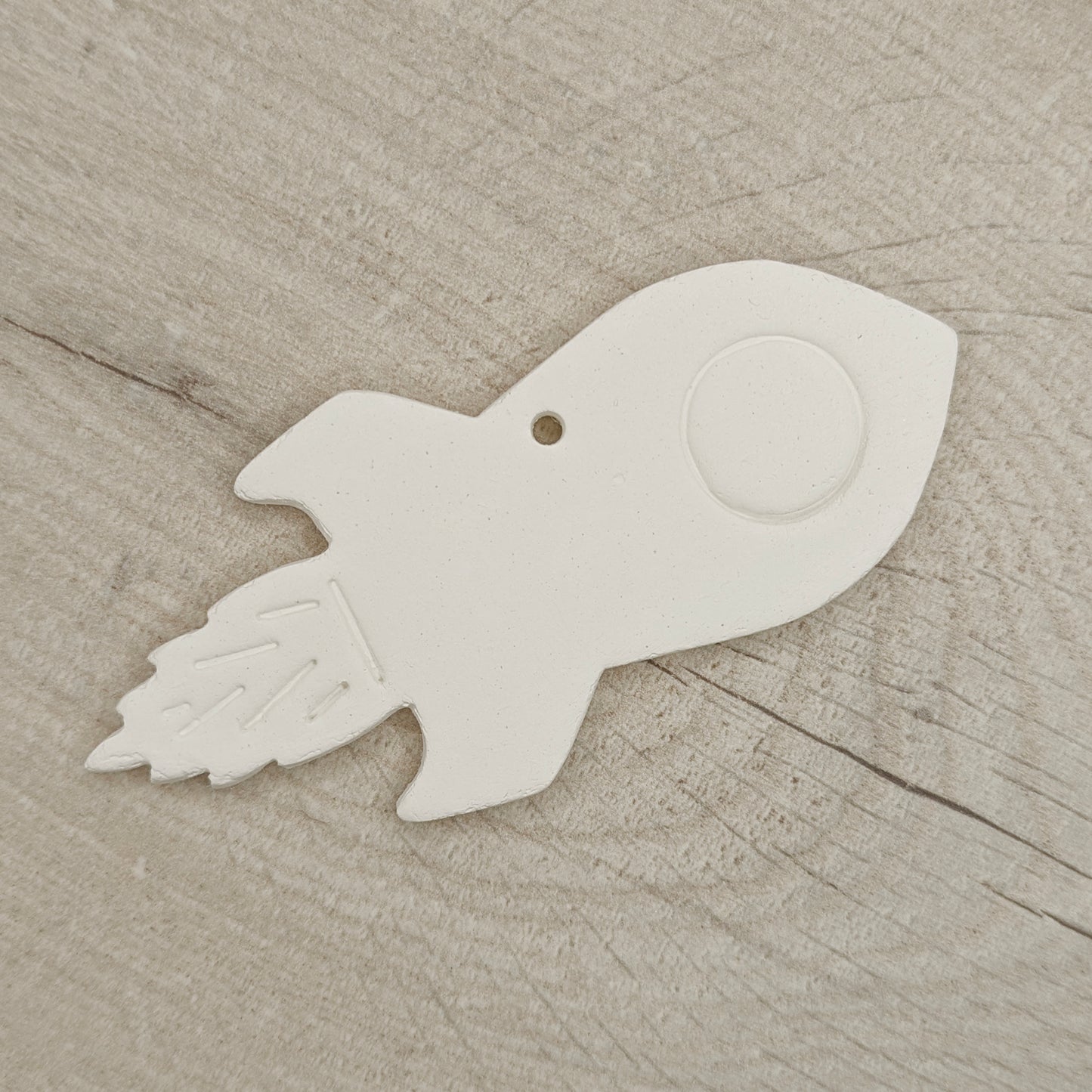 White clay rocket-shaped ornament on a wooden surface