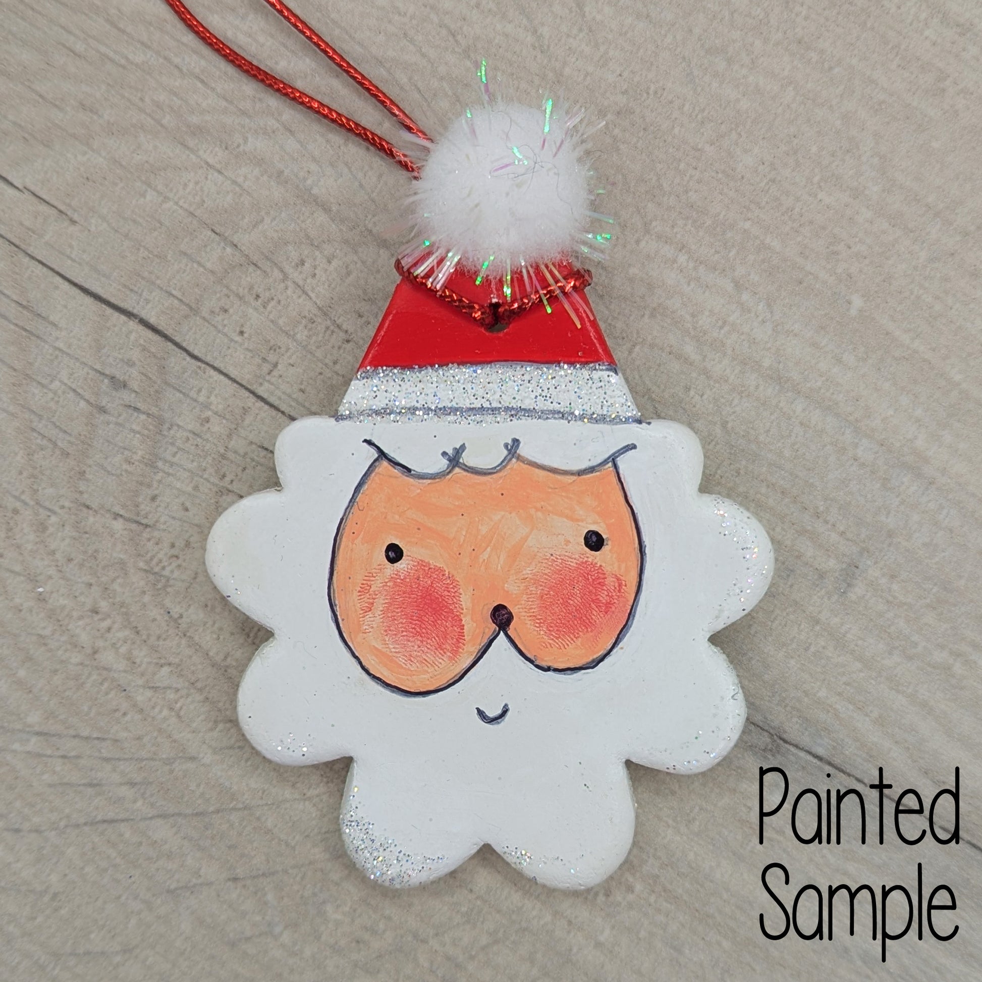 painted sample of santa clay decoration, painted in acrylic, with sharpie pen details, and a pom pom on top of his hat