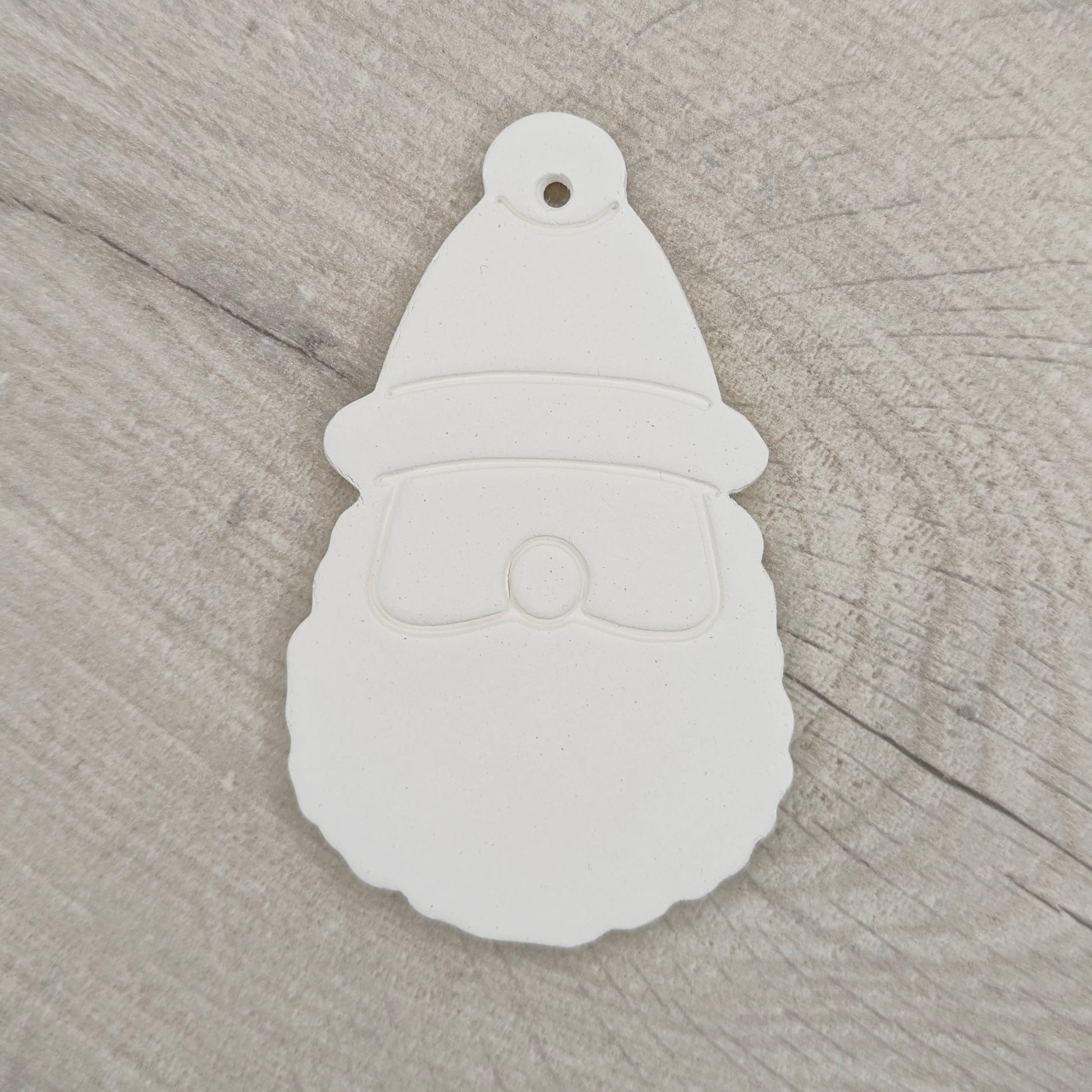 a clay decoration in the shape of santa head and hat on a wooden background