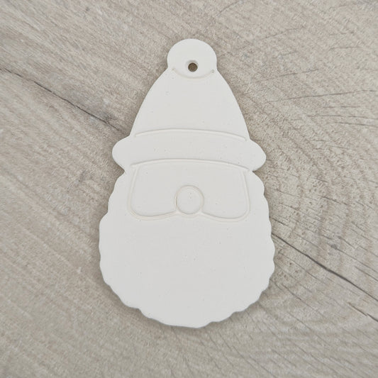 a clay decoration in the shape of santa head and hat on a wooden background