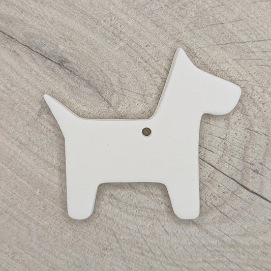 white air dried clay decoration in the shape of a scotty dog, shown on a light wood background