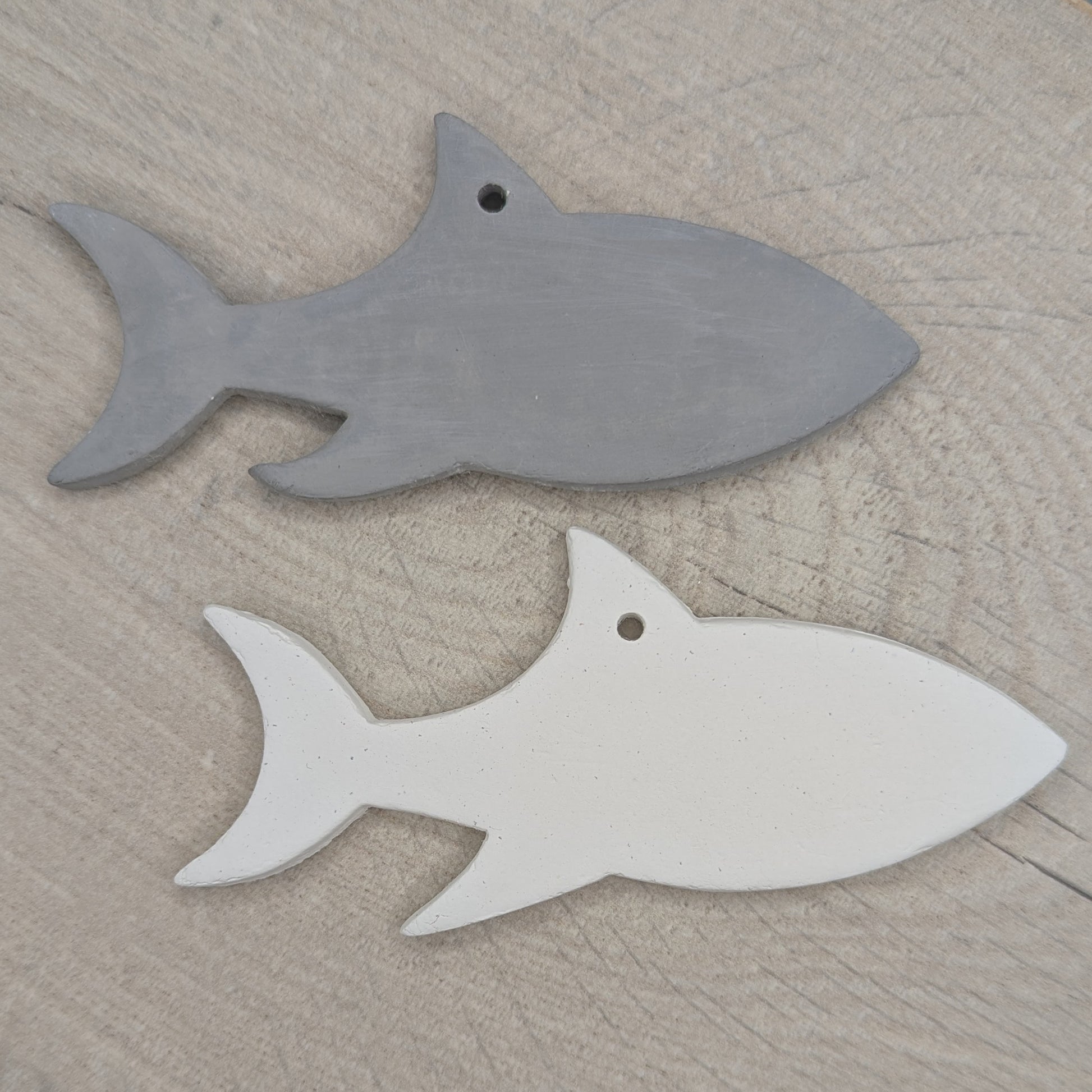 Two shark shaped clay decoration to show difference in coloured clay - displayed on a wooden surface