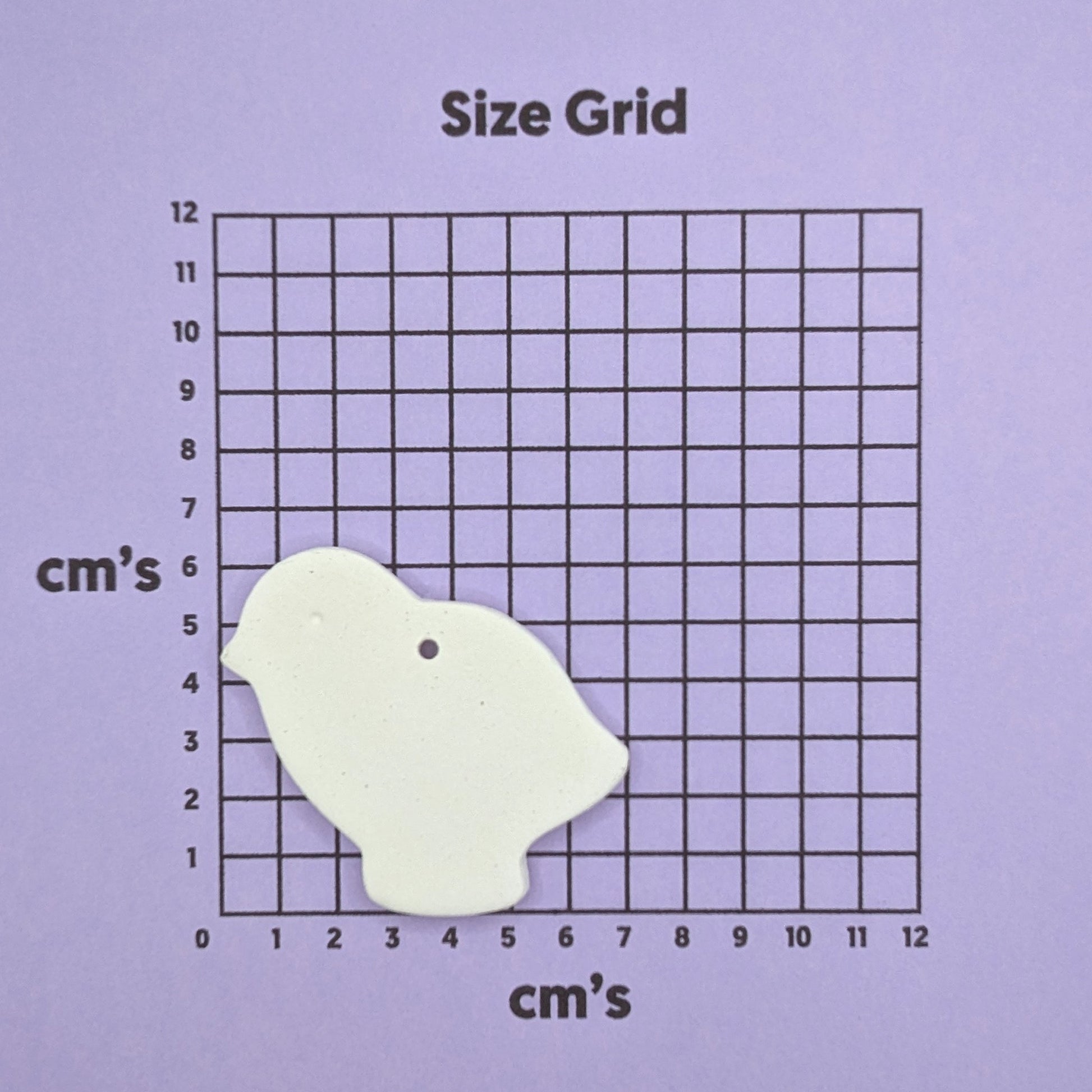 small clay chick decoration on a size grid chart